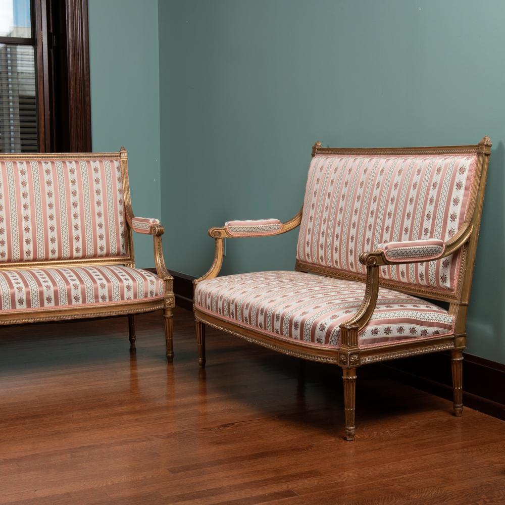 Pair of 19th c. French Louis XVI Giltwood Settees: A pair of late-19th century French gilt salon settees in the Louis XVI style. Silk striped floral upholstery. Each measures 39" x 51" x 27". Provenance: The Shirley Bush Helzberg and Webster House col