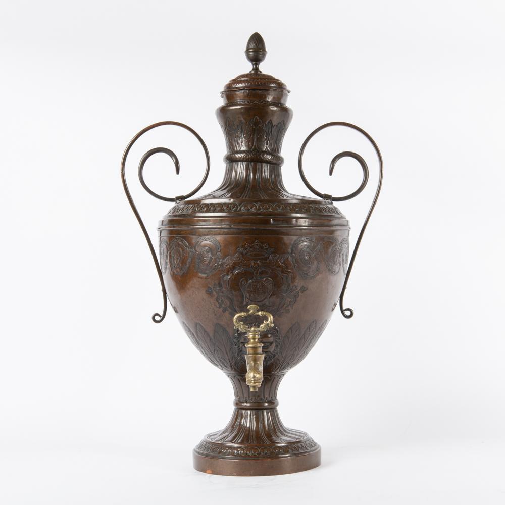 19th c. Copper Beverage Dispenser, French Heraldry: A large copper beverage dispenser with hand-chased detail, scroll amphora form, with central French royal coat-of-arms motif. The brass spout, decorated with dolphin motifs, protrudes from a lion's fa
