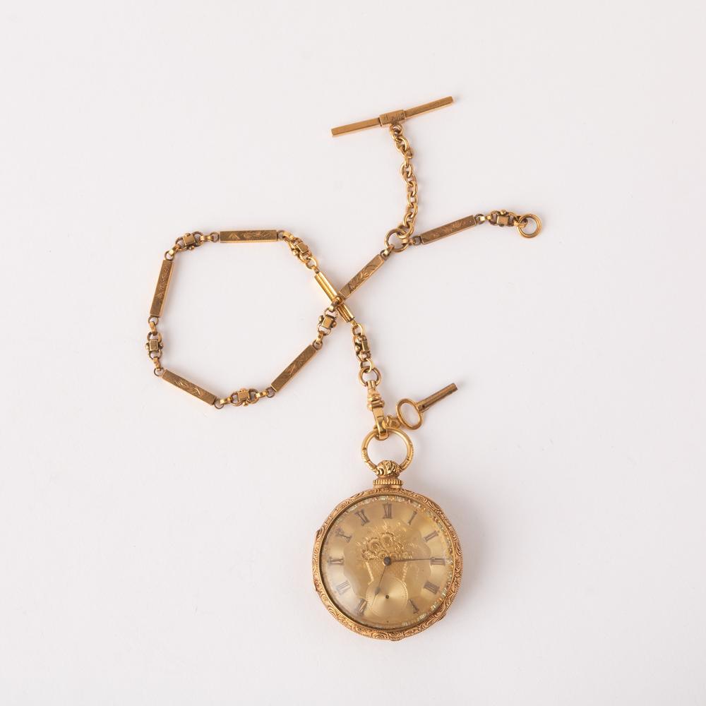 18K Gilt Dial British Key Wind Pocket Watch: An 18K yellow gold key wind pocket watch with an open face gilt embossed dial with a flower basket in the center. Roman Numerals for the hours, and a seconds register missing the seconds baton. The ca