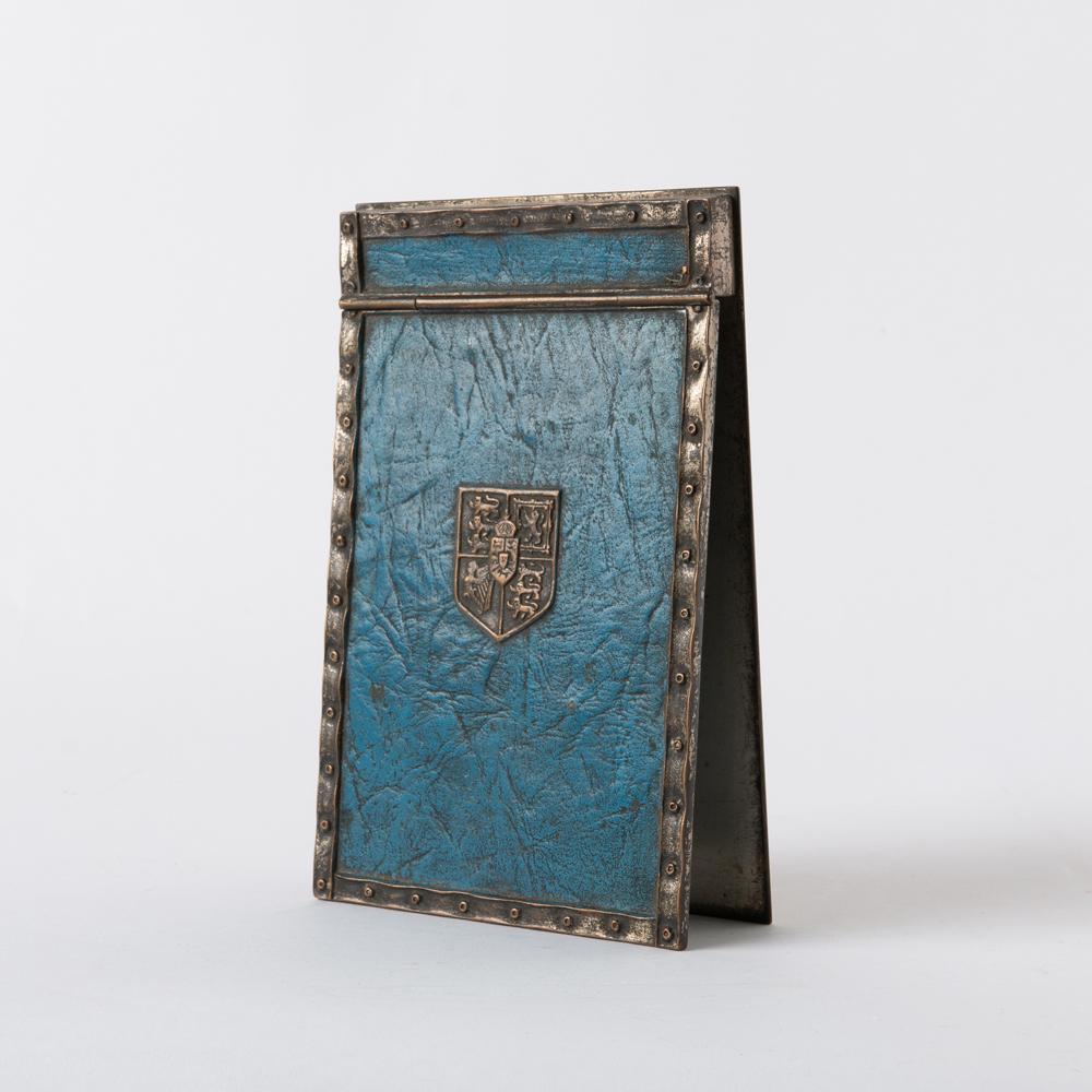 Tiffany Studios 'Heraldic' Notepad Cover: A Tiffany Studios "Heraldic" pattern memo or notepad cover, silver plate with blue patination and molded wrinkle texture mimicking leather, decorated with Queen Victoria's Hanover coat-of-arms. M