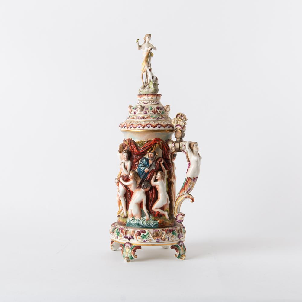 Capodimonte 19th Oversized Bacchanal Stein with Diana: A large Capodimonte (Italy) soft-paste porcelain stein with extensive figural high-relief, including a Baccanalalian frieze and a finial of Diana the Huntress. Secondary motifs include small 
