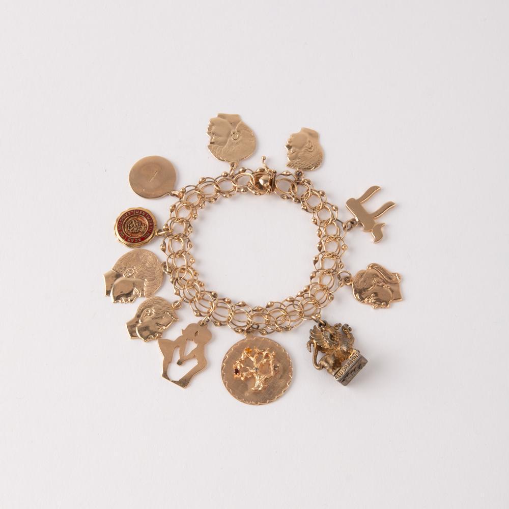 14K Charm Bracelet: 14K yellow gold looped charm bracelet by "POM" with 11 charms. nine of the charms are 14K yellow gold including five children's head charms each inscribed on the reverse, a Chia symbol, a tree with ge