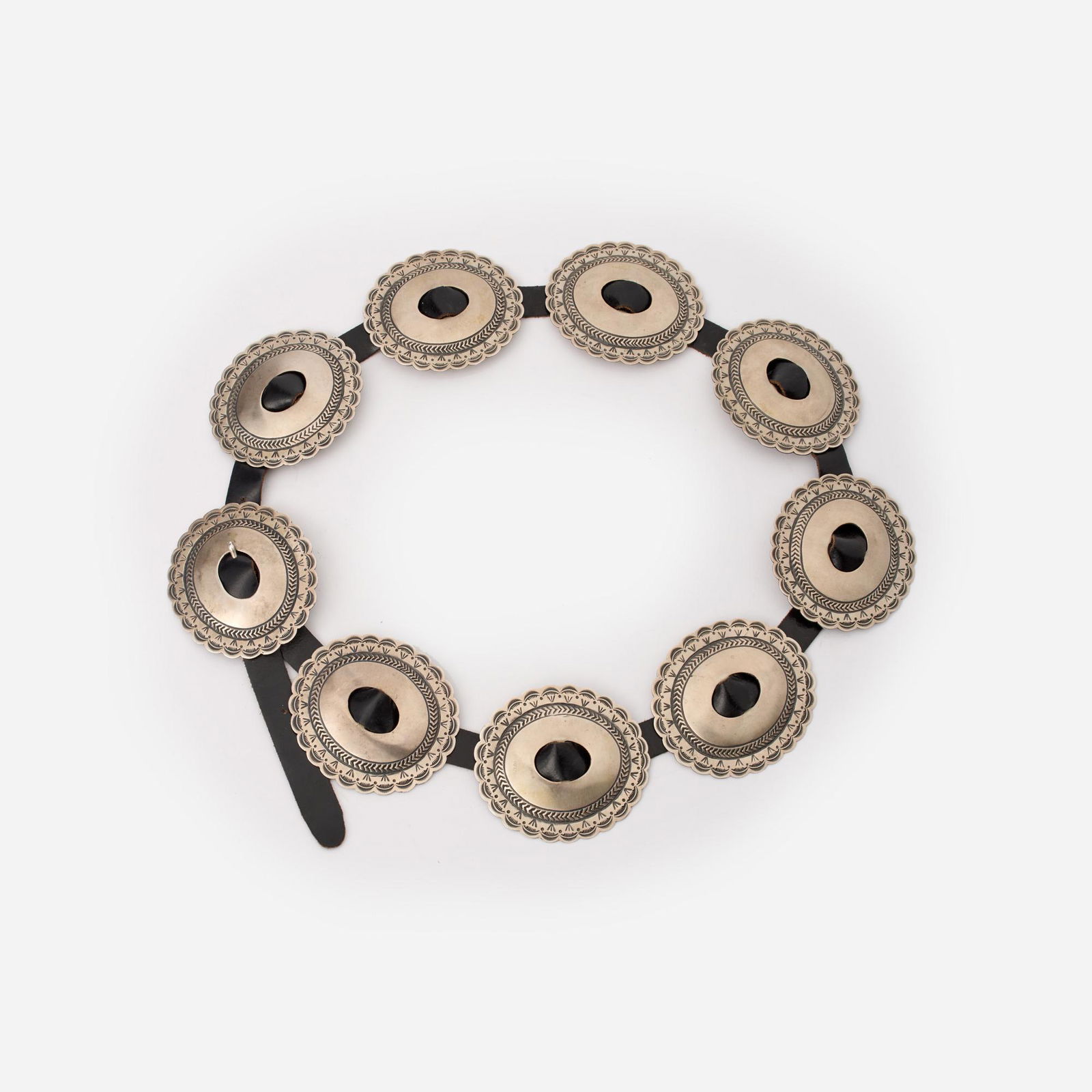 Navajo Sterling Concho Belt Signed R.J (Robert Johnson): Sterling and leather Navajo concho belt with nine large hand stamped scalloped conchos on a black leather belt. It is stamped on the reverse "R.J Sterling" which has been attributed to Navajo