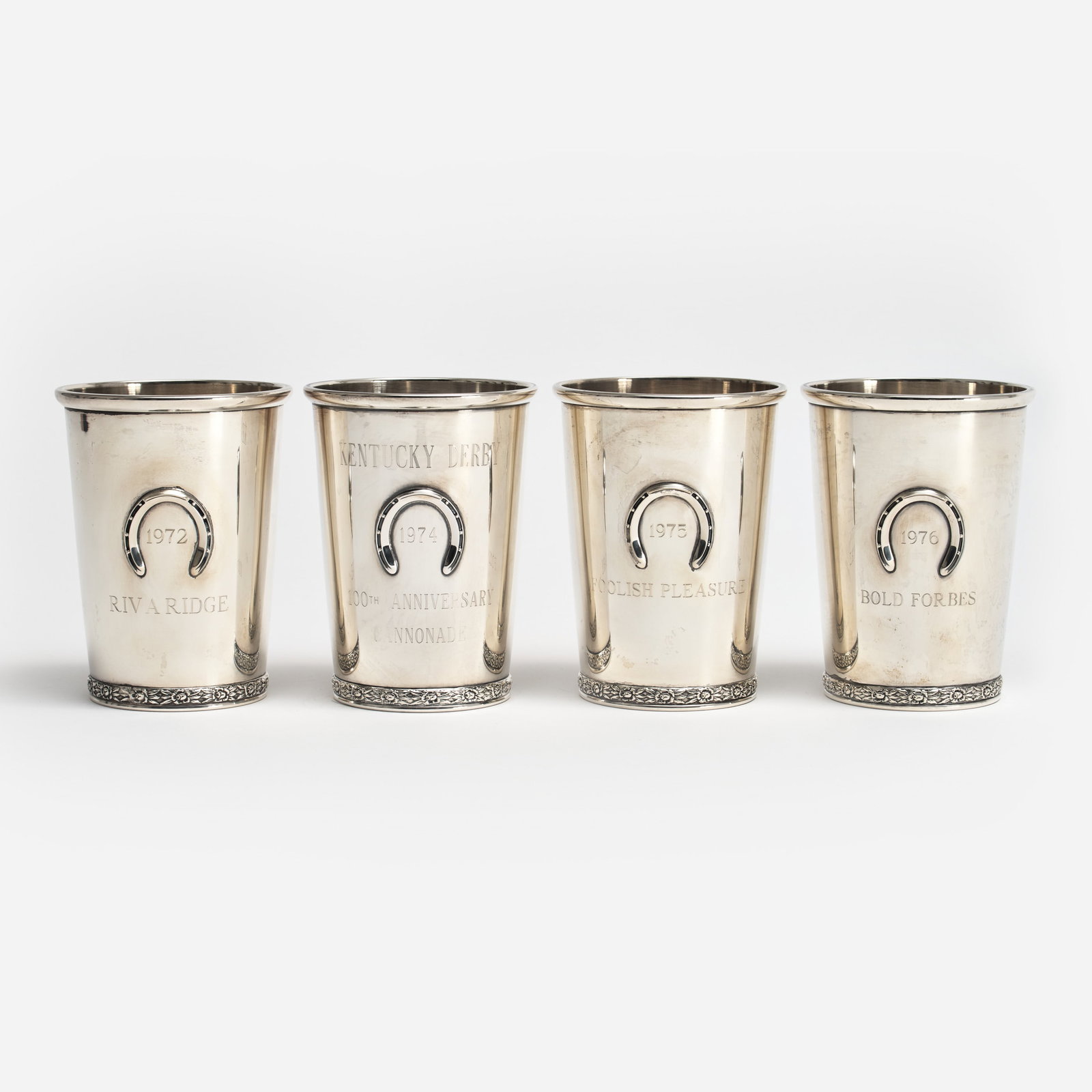 4 Kentucky Derby Sterling Julep Cups (1972, 1974, 1975, 1976): Four sterling mint julep cups engraved with the winners of the Kentucky Derby. Produced by BWK (Brown Waterhouse Kaiser, Louisville, KY), these julep cups with an applied horseshoe design were the off