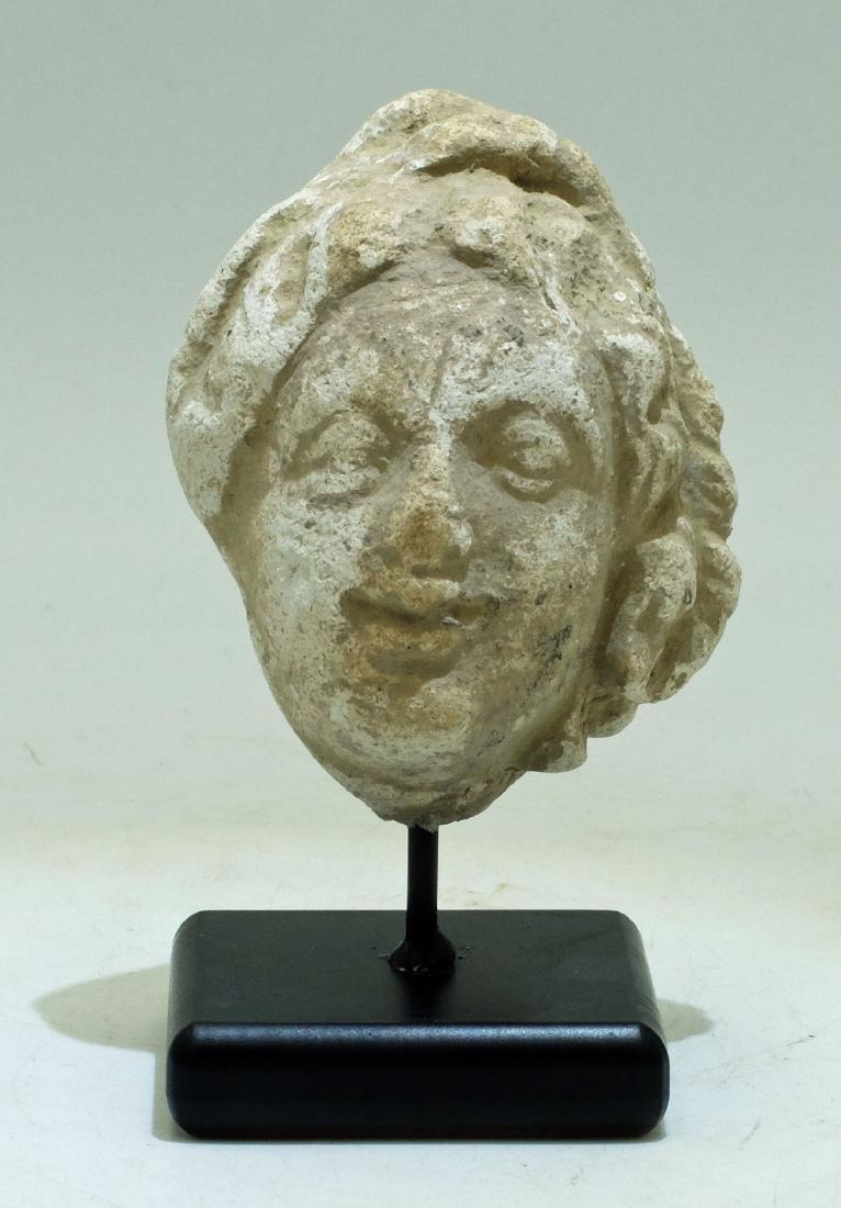 Gandharan Stucco Bust, Indus Valley, ca 300-400 AD: A beautiful Gandharan stucco head from the Indus Valley, perhaps Hadda, ca. 300 - 400 AD. It is 3" high and portrays a youthful Bodhisattva with hair skillfully framing his face and loosely knotted at