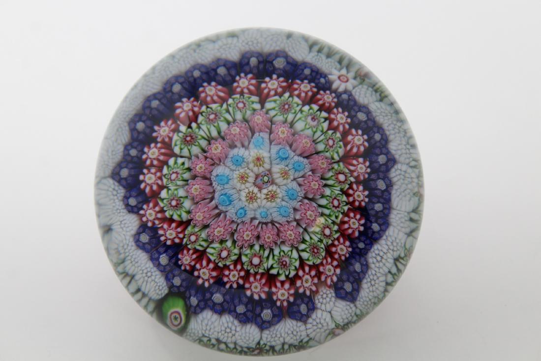 Clichy Concentric Millefiori Pedestal Paperweight: Clichy Concentric Millefiori Pedestal Paperweight. Eight rows of assorted canes in shades of green, purple, crimson, blue and whire with a tiny central composite cane, set in a basket of elongated cri