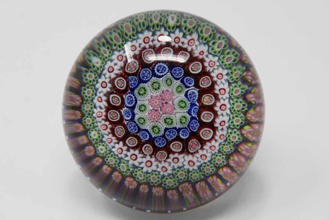Clichy Millefiore Pedestal Paperweight: Clichy Millefiore Pedestal Paperweight. The clear glass set with six rings of assorted millefiori canes in shades of red, blue, green and pink with a central cluster of four pink and white floreetes, 