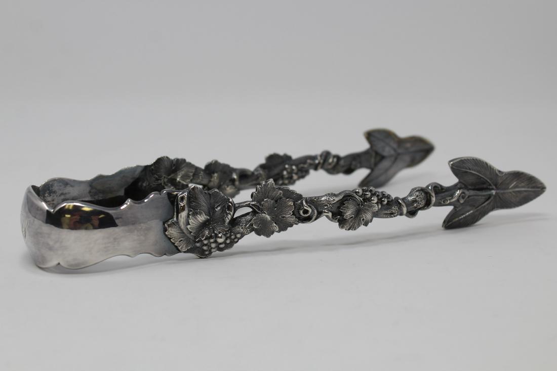 Large New York Coin Silver Tongs: American, mid 19th century, grape and vine handles with leaf form terminal with grips and marks for Ball, Black & Co. Length: 8 inches.