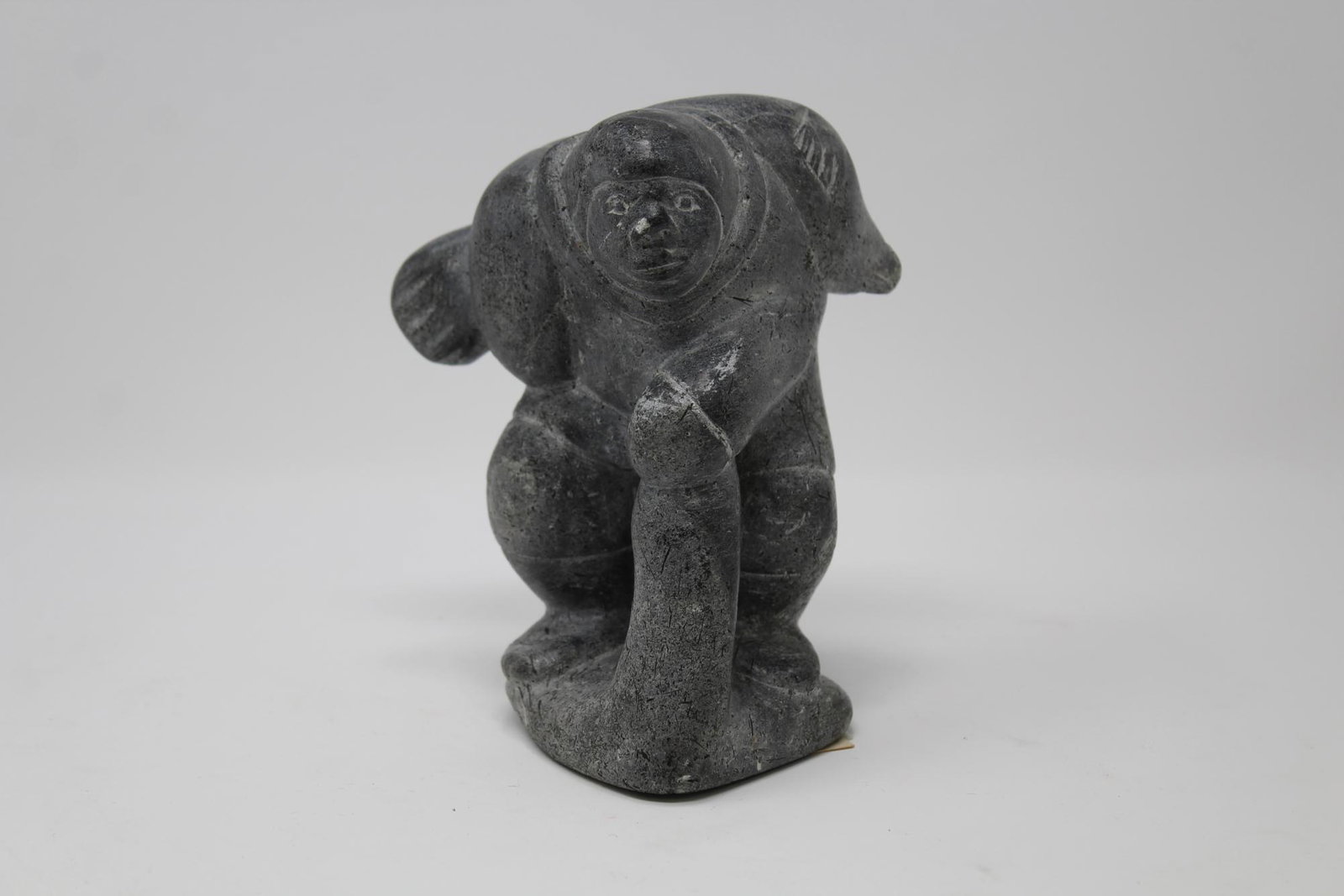Levi Alasua Pirti (Canada, born 1926): Levi Alasua Pirti (Canada, born 1926) Akulivik stone carving of Eskimo hunter with seal. Original gallery label. Height: 5.5 in. Approx. Weight: 3 lbs