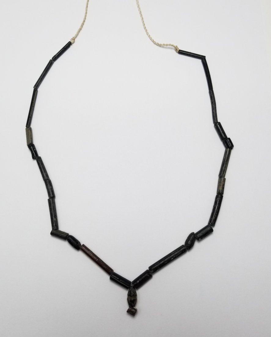 Strand of Roman Glass Beads, 2nd - 4th C AD: A strand of Roman glass beads, ca. 2nd - 4th Century AD. It is 17.5 inches long and consists of slender black tube beads. (B225)