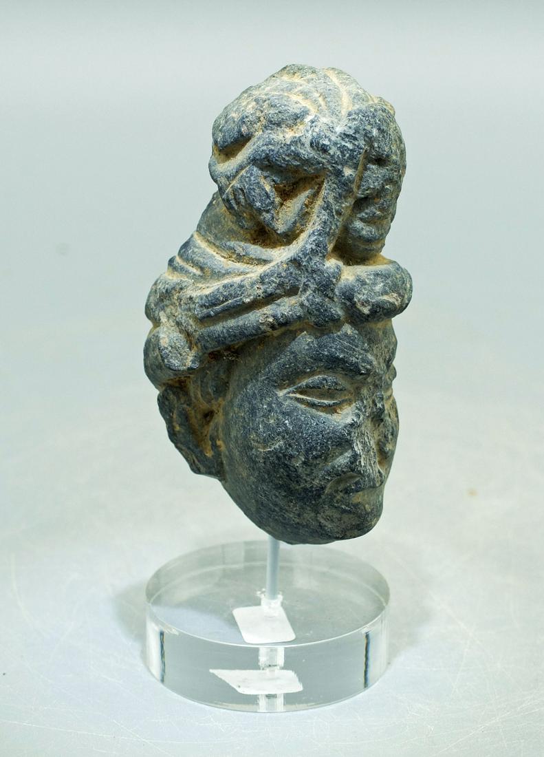 Gandharan Stone Head - Indus Valley, 3rd - 4th C.: A fine Gandharan stone head from the Indus Valley, ca. 3rd - 4th Century AD. This nicely detailed example is 2-3/4 inches high and depicts an individual with a fancy coif that conceals a small face. B