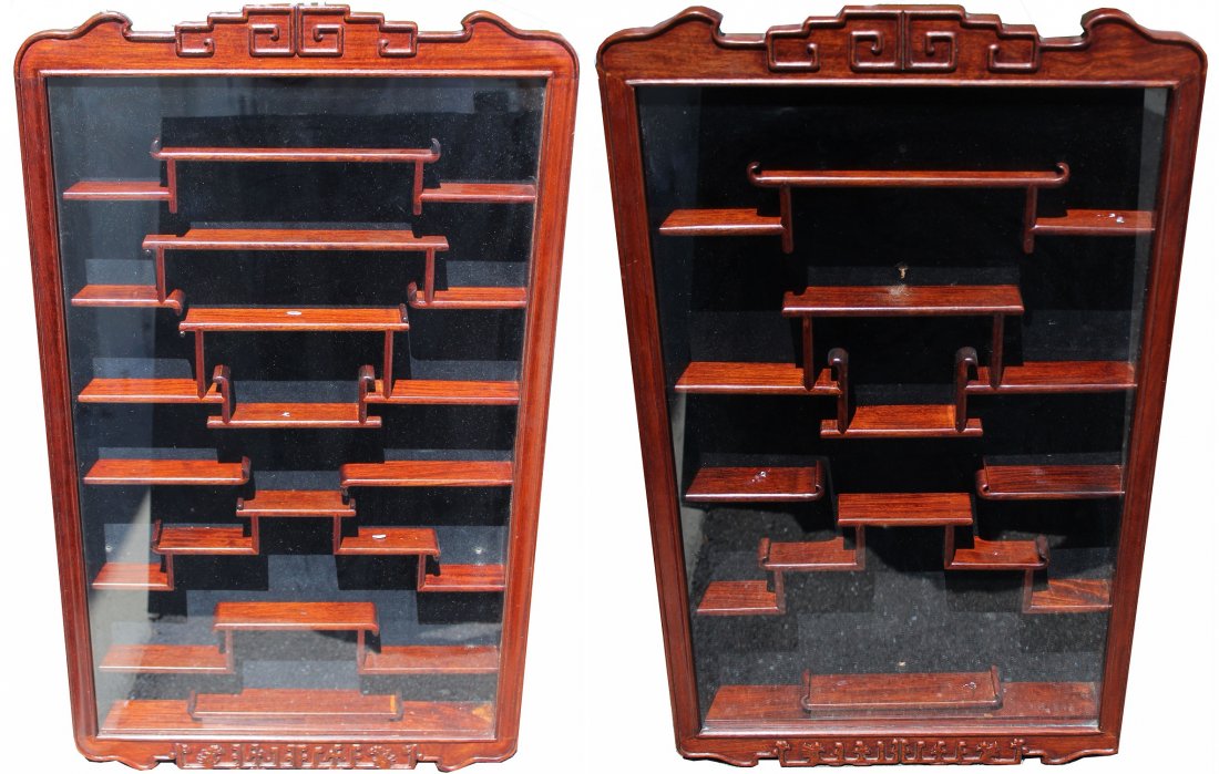 (2) Glass Front Chinese Hardwood Netsuke Displays: Pair, Lacquered WoodGlass Netsuke Display Cases. Each Cabinet constructed with a black velvet lining behind tiered shelves. Finished with a scalloped crown and base. Provenance: Bonhams, San Francisco
