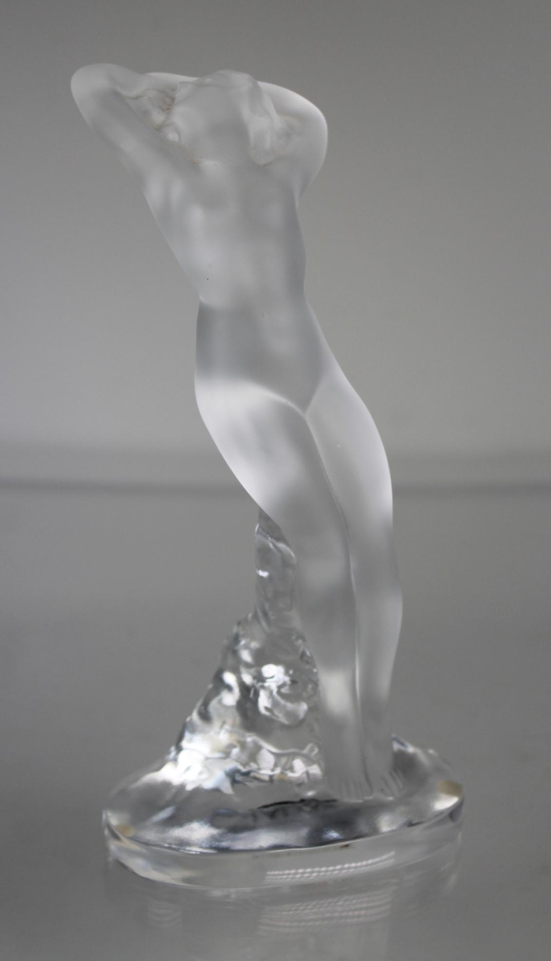 LALIQUE "Danseuse Bras Baisse" Figure: LALIQUE French molded & frosted crystal 'Danseuse Bras Baisse' figure of nude female dancer. Etched Lalique France signature to edge of base. Comes with original box. Box Size: 5 x 7.5 x 12 in.