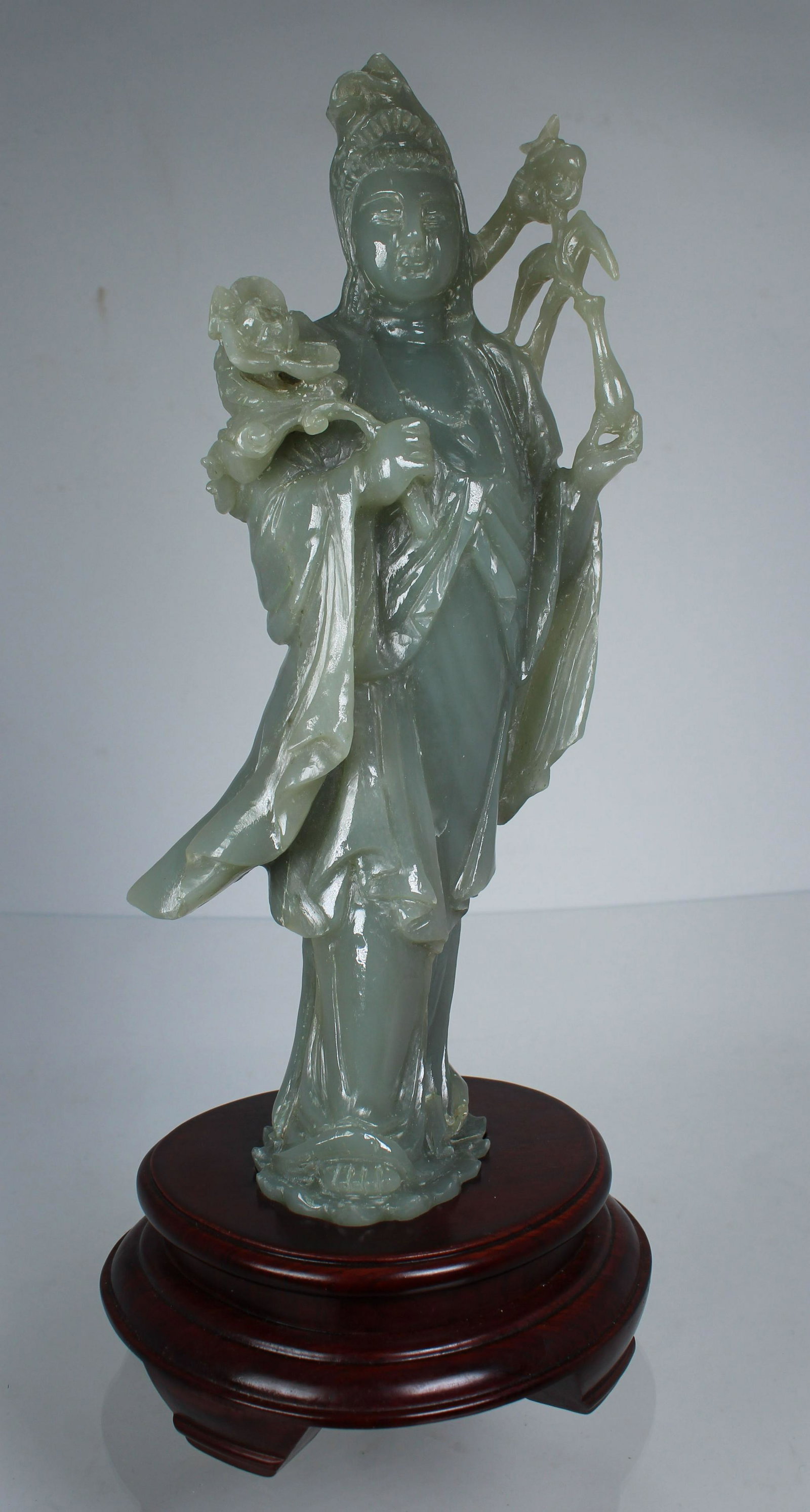 Chinese Carved Jade Guanyin on Wood Stand: Chinese Carved Jade Guanyin on double lotus form base. Standing on a carved/fitted wood base. Total Height: 12.5 in.