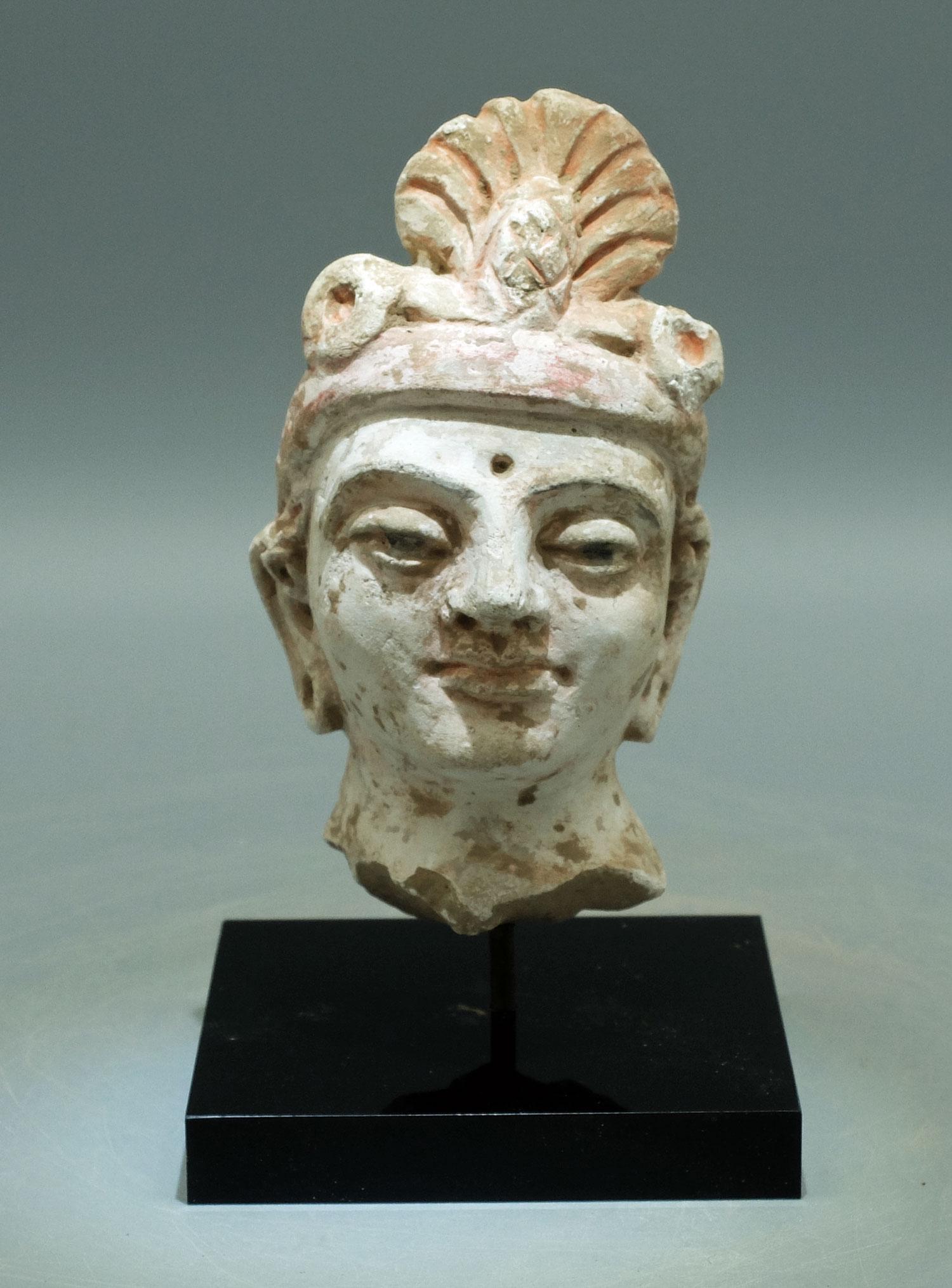 Gandharan Stucco Head - Indus Valley, 4th-5th C: A choice Gandharan stucco head from the Indus Valley, ca. 4th - 5th Century AD. This large example is 4-1/8 inches high and portrays a Bodhisattva with elongated ears and pierced lobes, wearing an orn