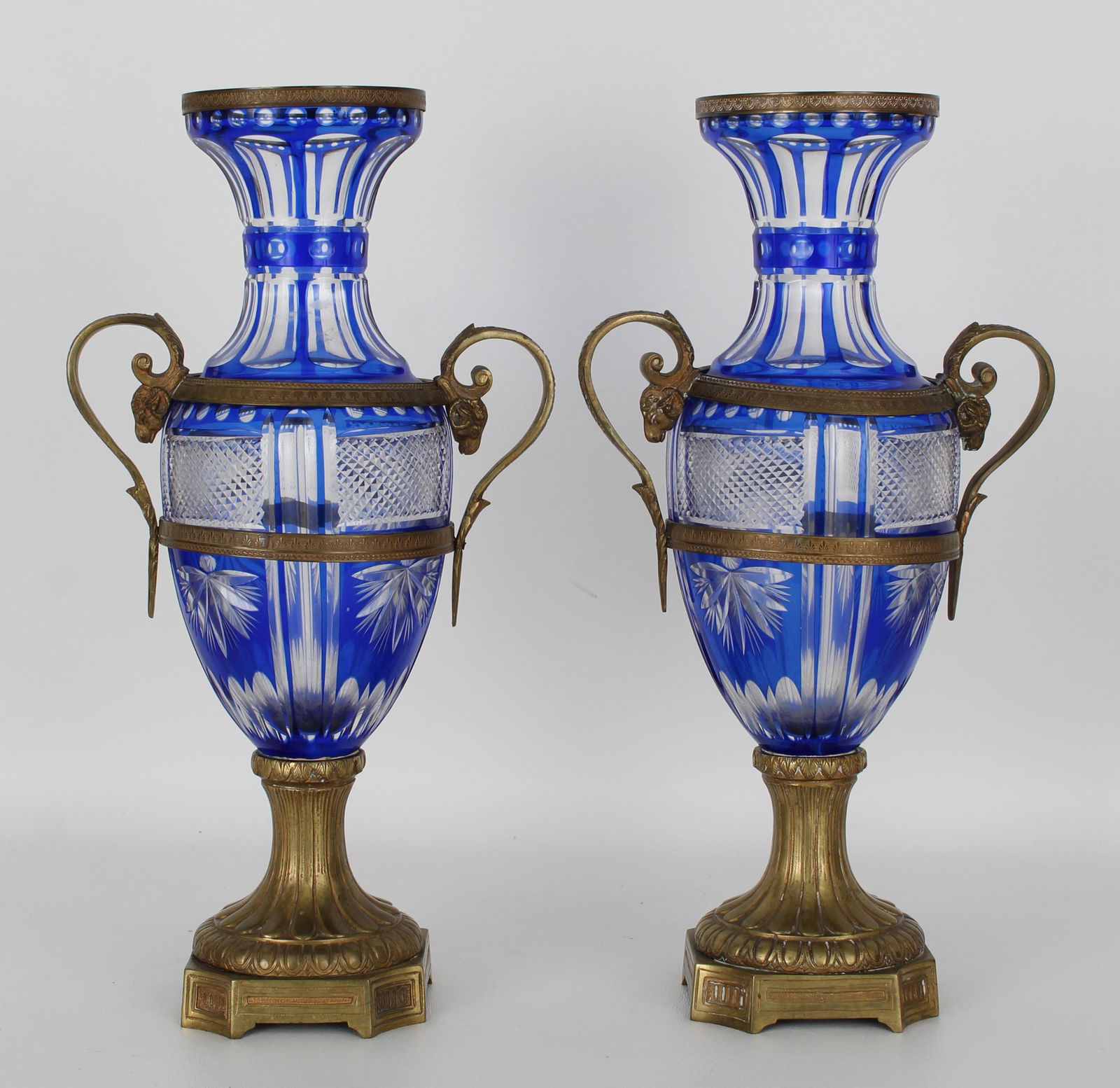Pair of French Bronze and Cobalt Cut Glass Urns: Pair of French Empire-Style Bronze and Cobalt-Plated Cut Glass Urns, first quarter 20th century, on molded bronze bases, the cobalt cut to colorless glass vases decorated with panels and diamond-point