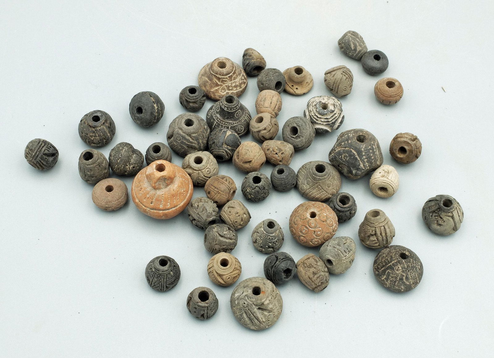 Collection of 50 Exquisite Manteno Spindle Whorls: A collection of 50 exquisite Manteno spindle whorls from Ecuador, ca. 1000 - 1500 AD. Each is delicately incised, depicting a wide variety of zoomorphic designs, mythical creatures and assorted geomet