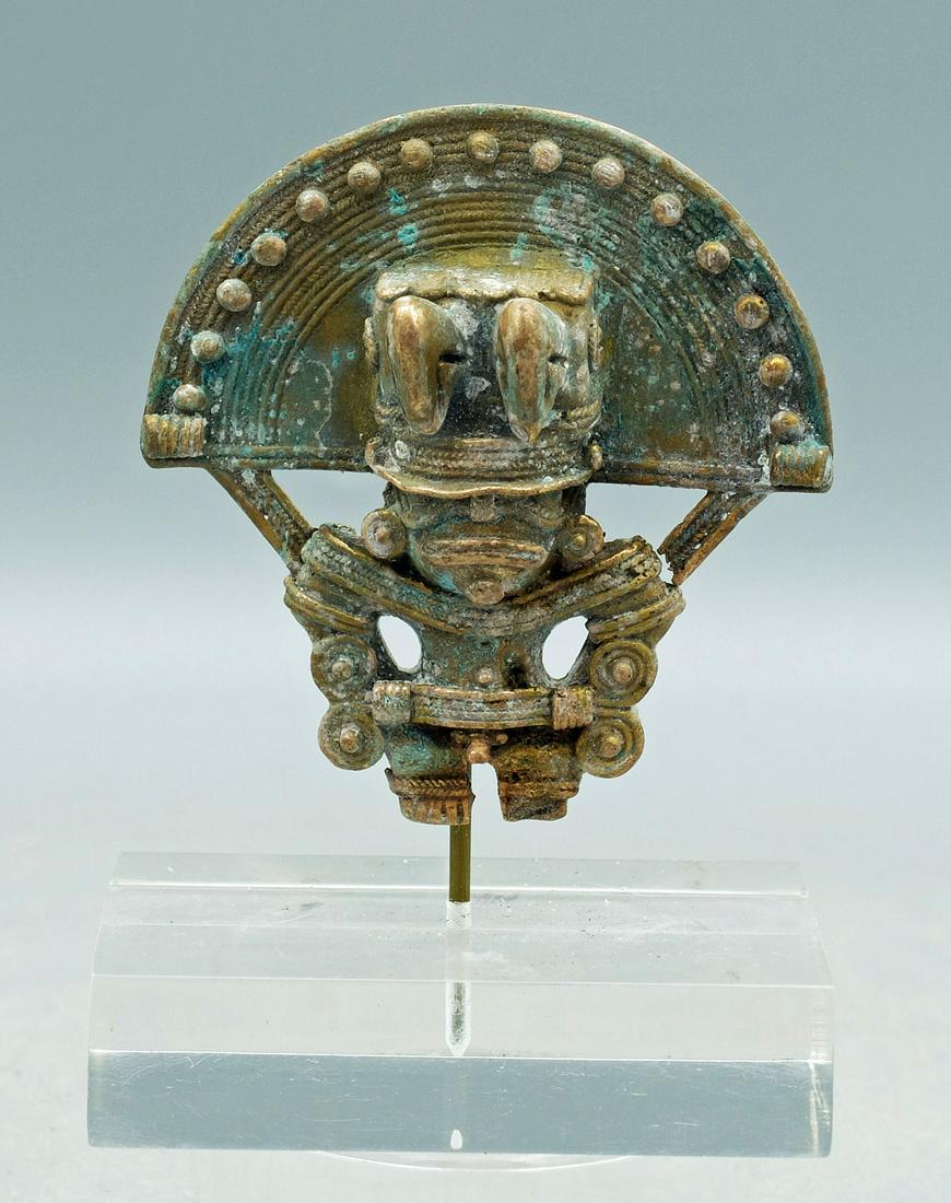 Tairona Tumbaga Pendant - Colombia: A choice Tairona tumbaga pendant from Colombia, ca. 1000 - 1500 AD. It is 3 in. high and portrays a shaman wearing a fancy ceremonial headdress consisting of two bird heads and a solar symbol. He is l