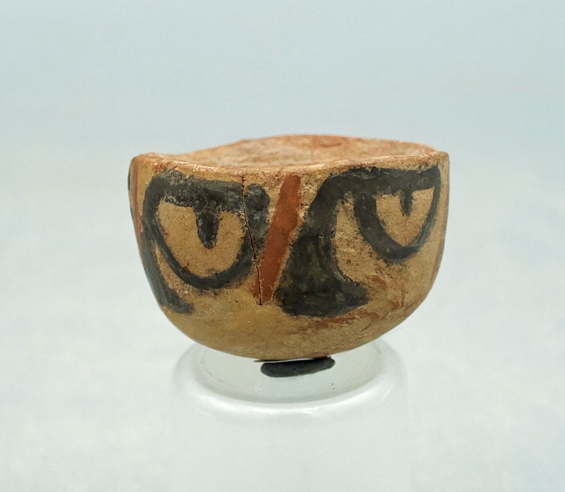 Nazca Votive Bowl - Peru: A rare Nazca votive bowl from Peru, ca. 500 - 600 AD. It is 1-3/4 in. in diameter and is decorated with a band of symbolic eye forms representing stylized trophy heads. Intact, good mineral deposits,