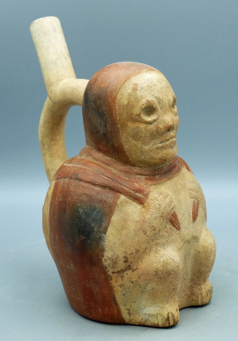 Moche IV ancestor figure from Peru: A choice Moche IV ancestor figure from Peru, ca. 450 - 550 AD. This excellent stirrup vessel is 8-1/4 in. high and portrays a deceased hunter carrying a deer to sustain him on his journey through the