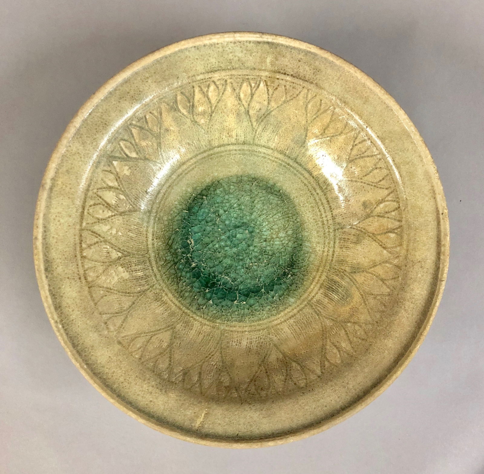 13th-14th C. Korean or Persian Celadon Bowl: A 13th-14th Century Korean or Persian Carved and Celadon Glazed Bowl. The interior carved with a band of Lotus Petals and having a pool of Celadon Glaze at its center. The exterior with running glaze