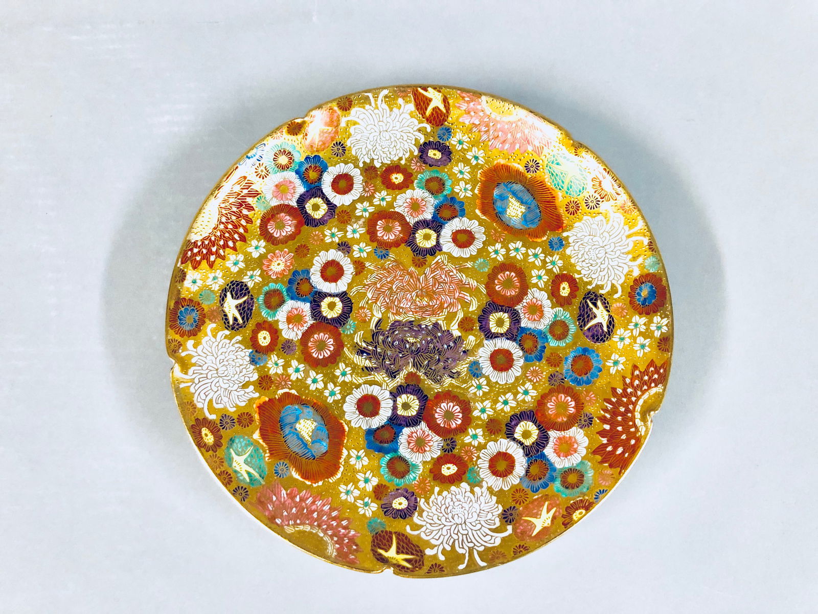 Japanese Satsuma Thousand Flowers Millefleur Plate: A Japanese Satsuma "Thousand Flowers" Millefleur Plate. The hand painted porcelain plate is decorated in relief flowers of many color on gold ground. Signed on the base. Diameter: 8.5 in.