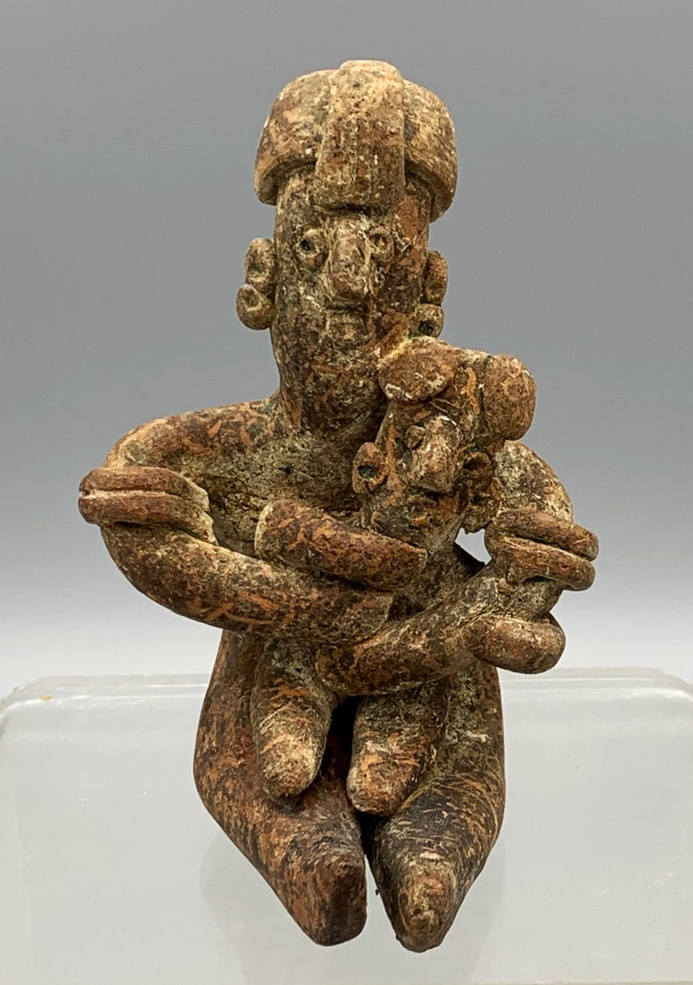 Colima maternal figure - West Mexico: An excellent Colima maternal figure from West Mexico, ca. 300 BC - 300 AD. It is 3-7/8 in. high and depicts a seated female cradling a child in her lap. She is adorned with a fancy headdress, multiple