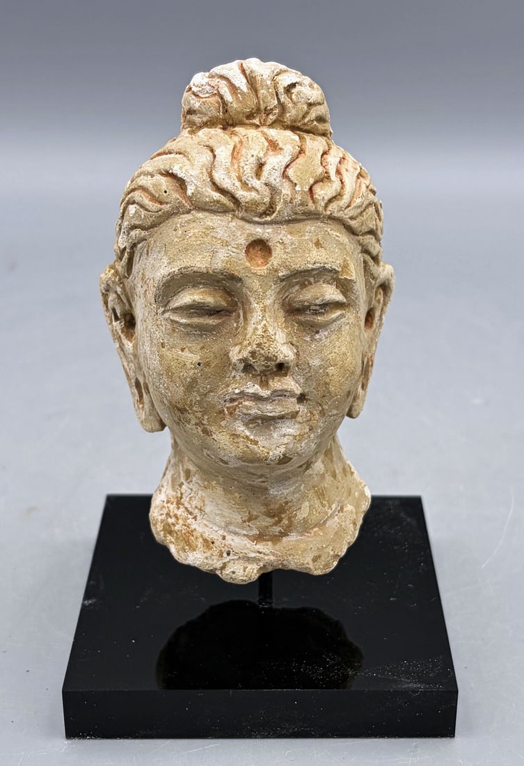 Gandharan stucco head - Indus Valley: A fine Gandharan stucco head from the Indus Valley, ca. 4th - 5th Century AD. This fine example is 4 in. high and depicts the Buddha. He is portrayed with a serene countenance and pronounced urna on t