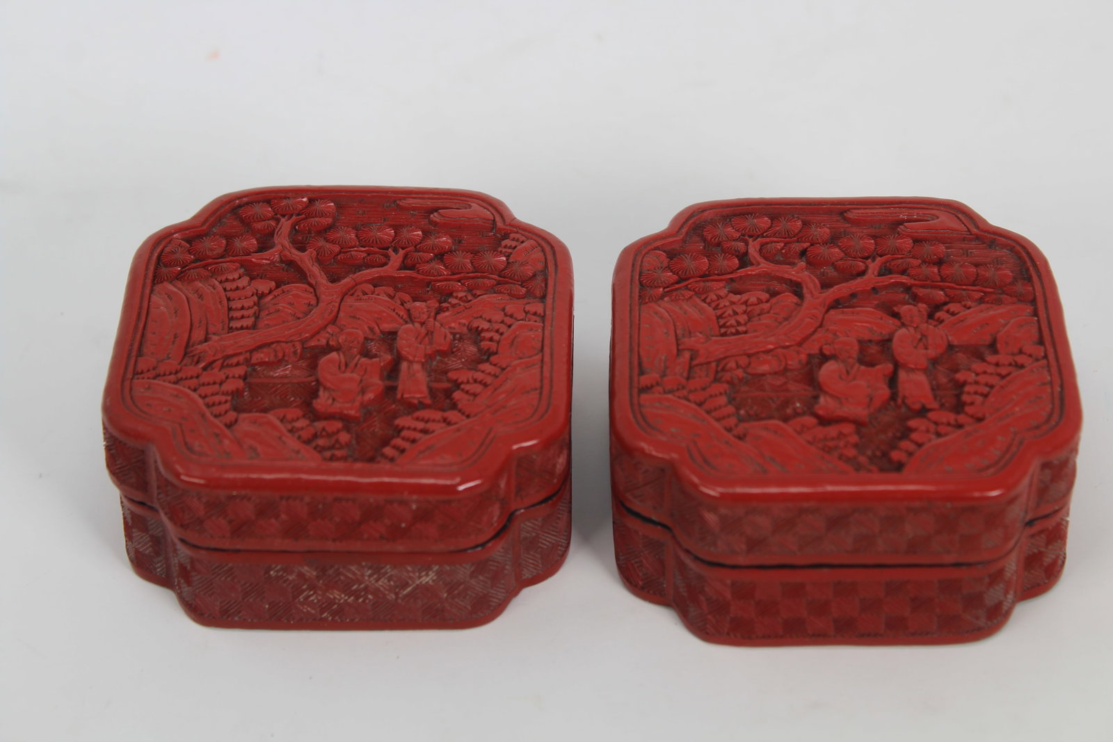 Pair, 19th C. Chinese Cinnabar Boxes - Qing: Pair, 19th C. Chinese Cinnabar Boxes. The covers carved in high relief with lovers in a garden standing beneath a prunus tree within a border of rich vegetation, the sides with a repeated square diape