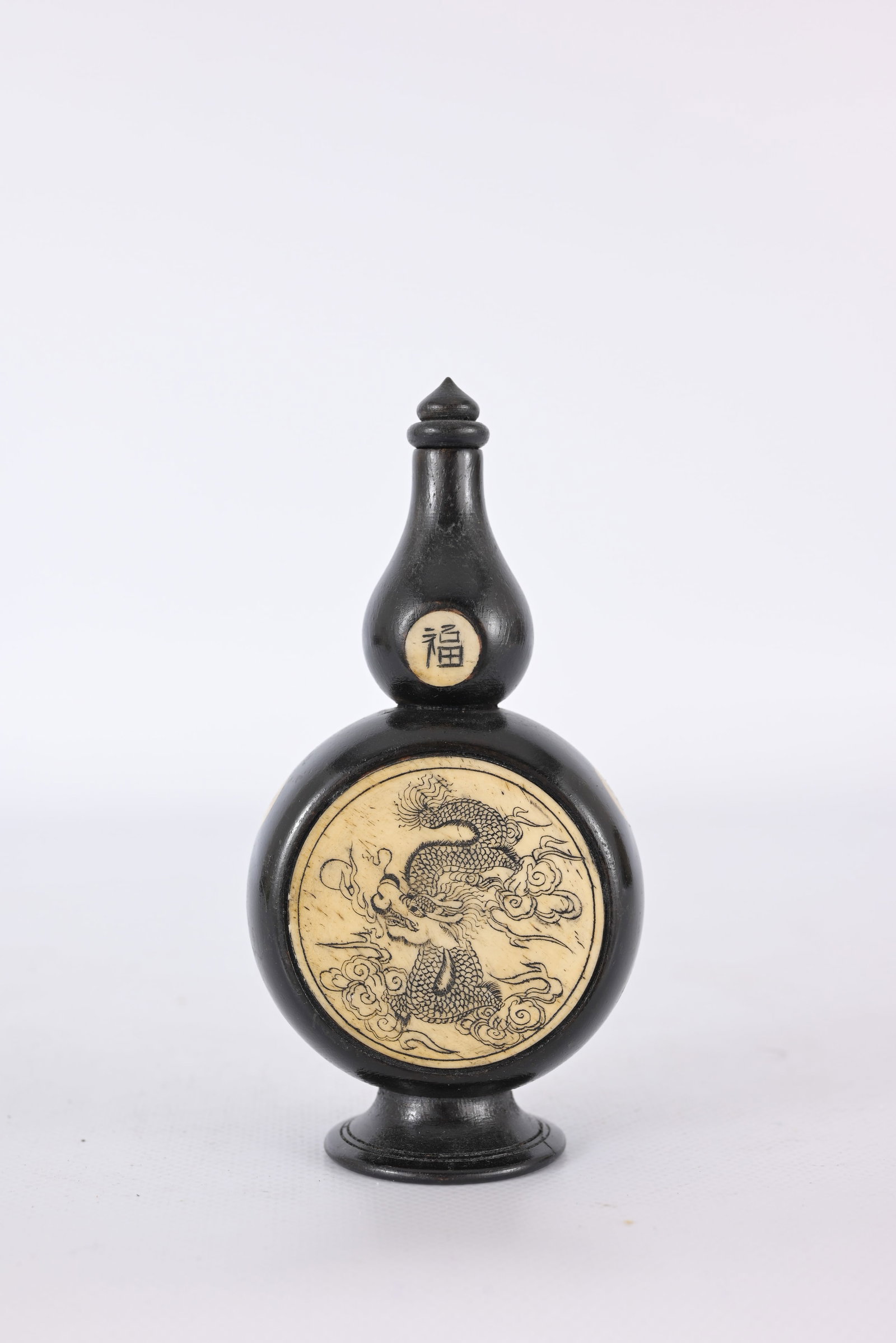 Chinese double-gourd snuff bottle: Chinese double-gourd snuff bottle made from dark buffalo horn featuring carved bone insets. Popular during the Qing Dynasty and into the 20th century, these bottles were designed to hold powdered