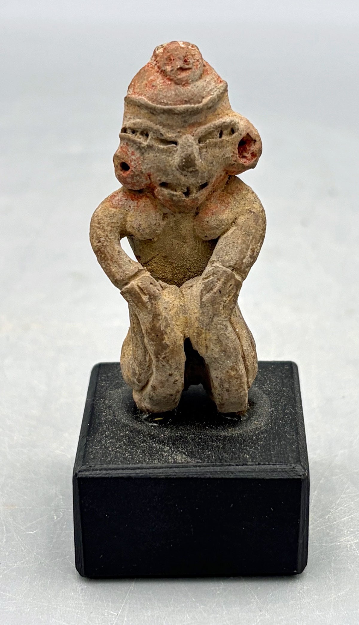 Las Bocas figure from Mexico: A choice Las Bocas figure from Mexico, ca. 1200-800 BC. This seated female is 2-1/4 in. high and is portrayed with hands resting on the updrawn knees. She is adorned with large earspools and a fancy