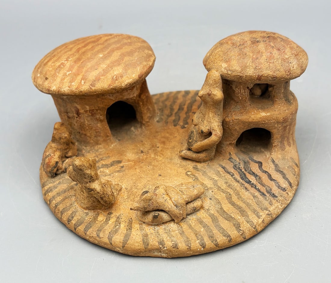 Colima village scene from West Mexico: An exquisite Colima village scene from West Mexico, ca. 300 BC - 300 AD. The scene features two buildings mounted on a 5-1/2 in. diameter platform, each containing an individual on the interior. The