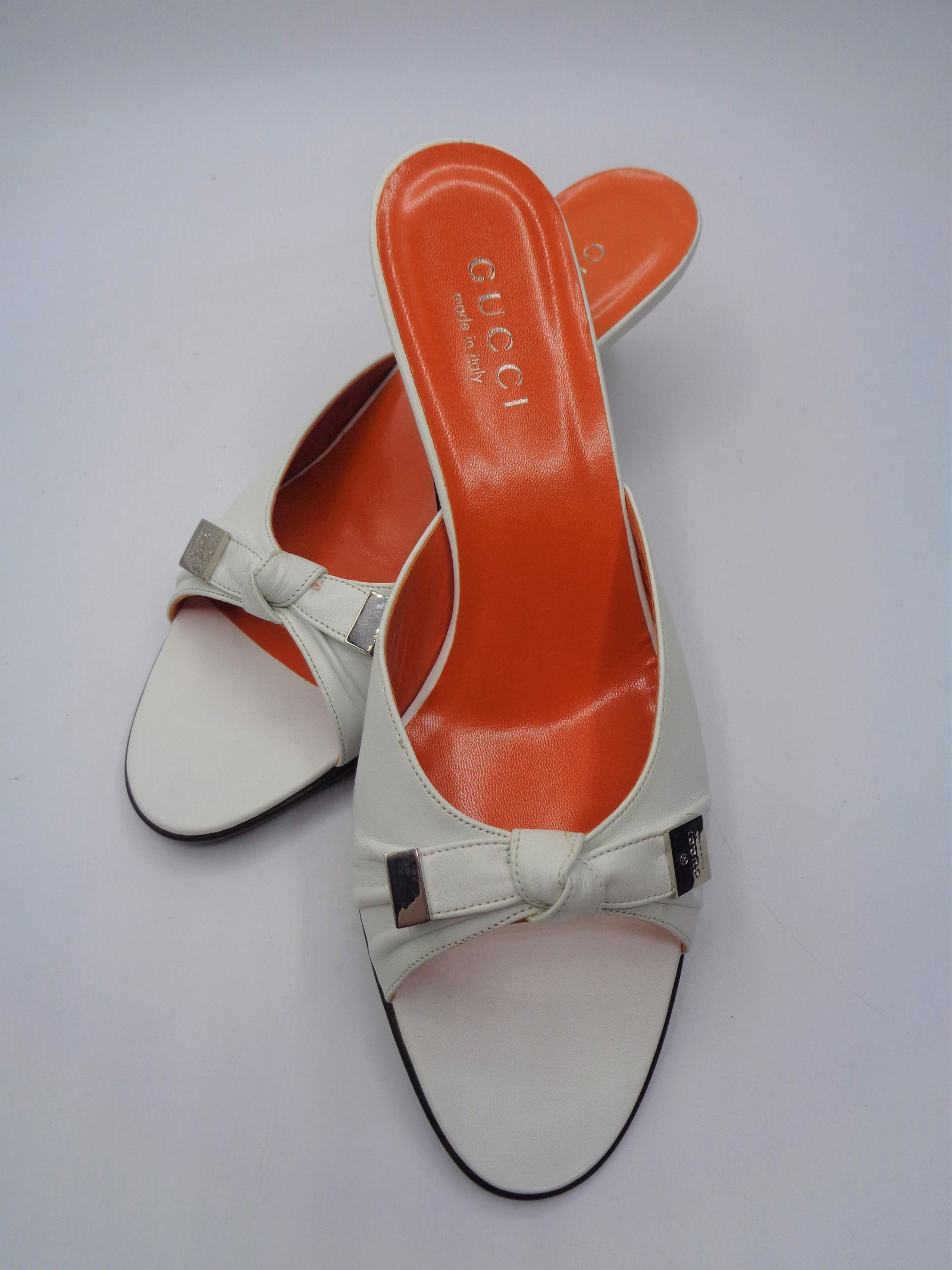Gucci Kitten Heel Sandals: White kitten heel sandals with silver accents. Orange sole with Gucci logo. Made in Italy. Size 8.