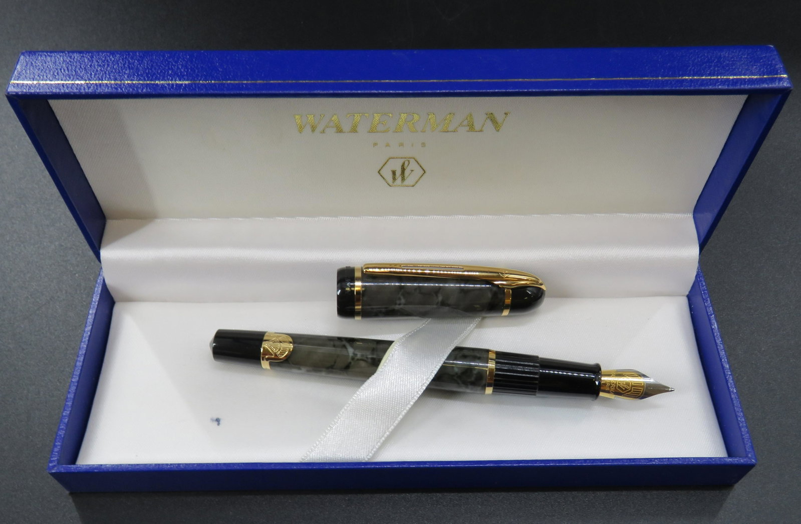 Waterman Paris Fountain Pen: Elegant Black/Gray Waterman fountain pen in original box. Beautiful gold accents. Pen stamped with Waterman. Item has a 5.25" Inch length. Excellent condition. Some minor staining on the inside of box