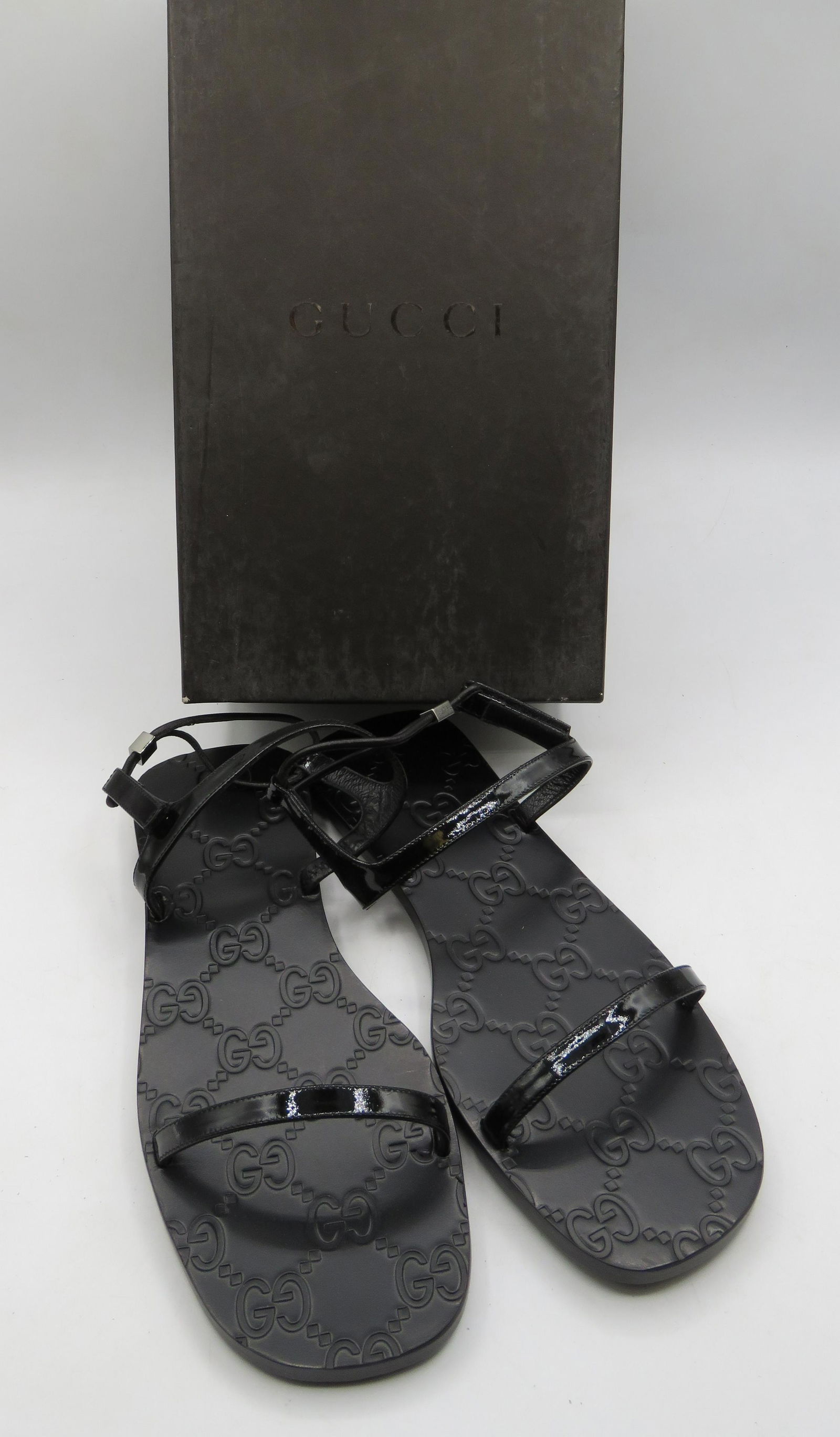 Gucci Womenâ€™s Sandals: Black, patent leather black â€œstrappy” sandals with gucci logo on sole. Made in Italy. Size 7.5