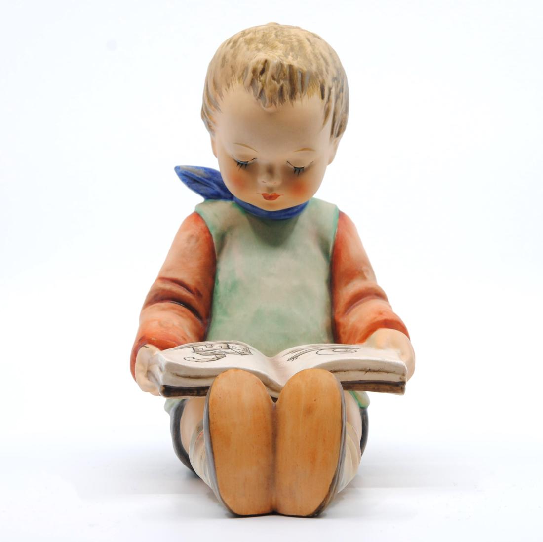 Goebel "Book Worm" Collector Figurine TMK-6: Goebel "Book Worm" figurine of a boy reading a book. Figurine of a young boy reading a book. The boy is wearing a red long sleeved shirt with a green vest, and a blue scarf. Imprinted M.J. Hummel on t