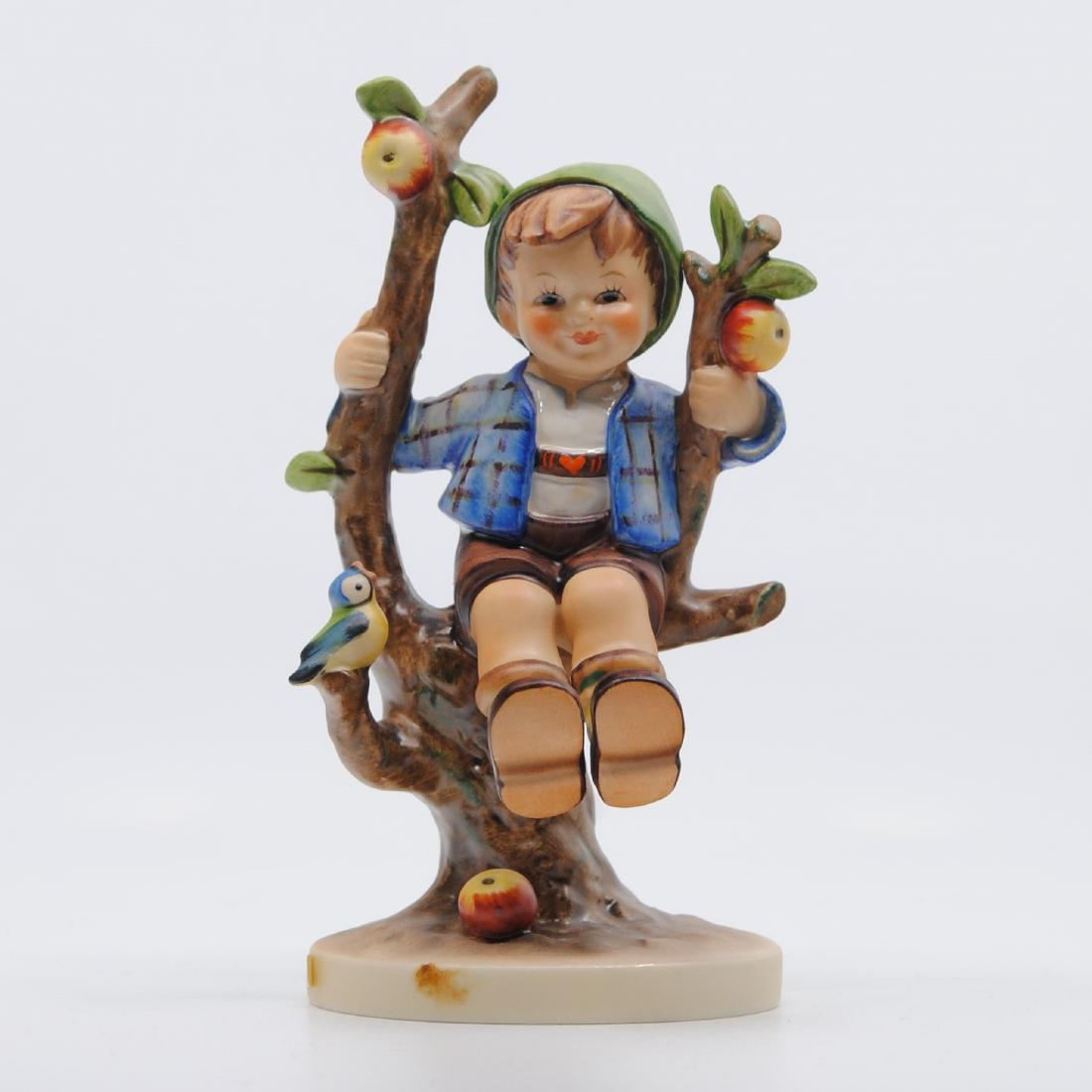 Goebel "Apple Tree Boy" Collector Figurine TMK-5: Goebel "Apple Tree Boy" figurine. Figurine of a little boy wearing a blue jacket and green hat, sitting on an apple tree branch. There is a little bird perched on one of the branches. Imprinted MJ Hum