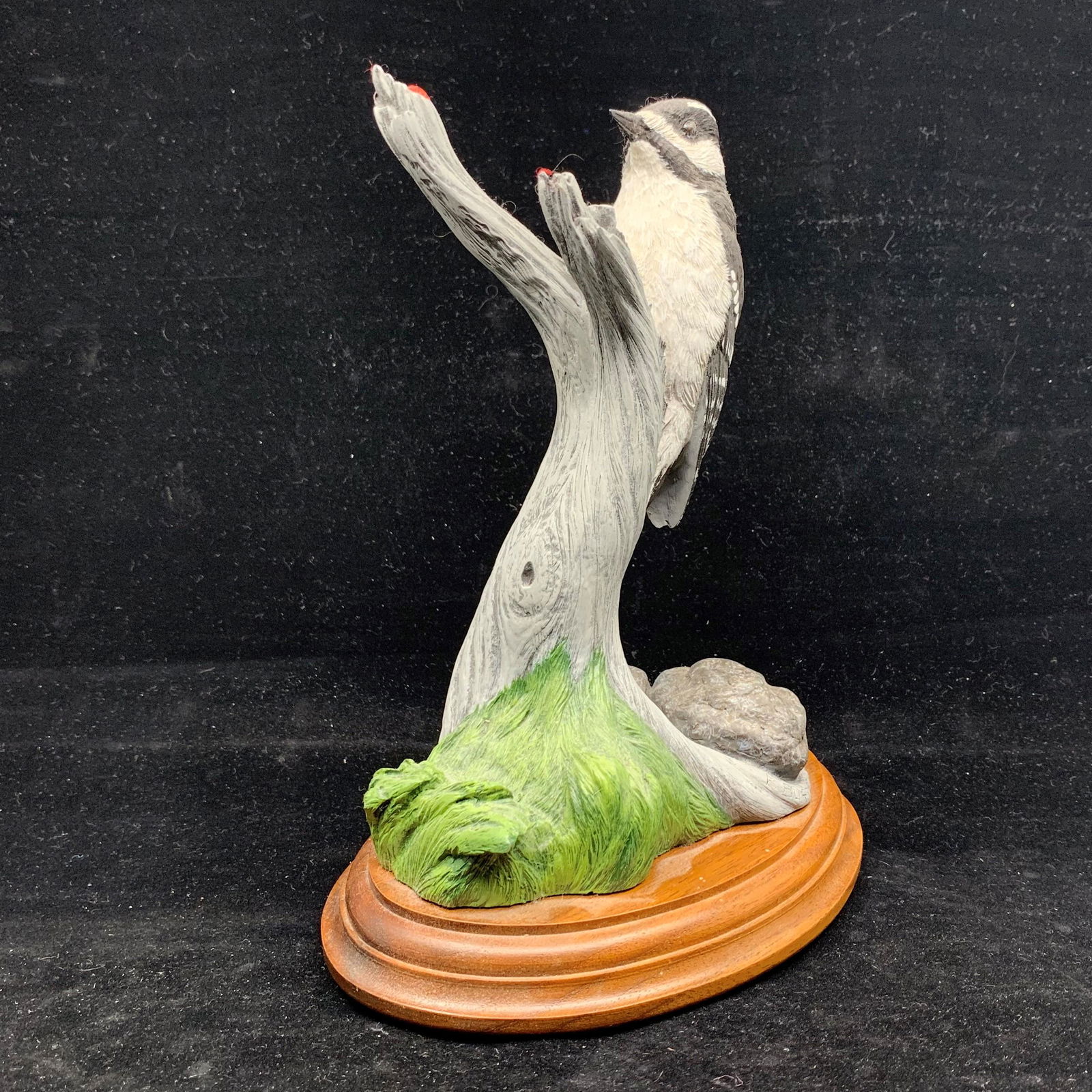 Paul Burdette's "Downy Woodpecker" AP 8/15: Paul Burdette's "Downy Woodpecker" Artist Proof 8/15. Very well done, this piece has been made on a wood base. The black, white and red downy woodpecker is perched on a branch, along with rocks and gr