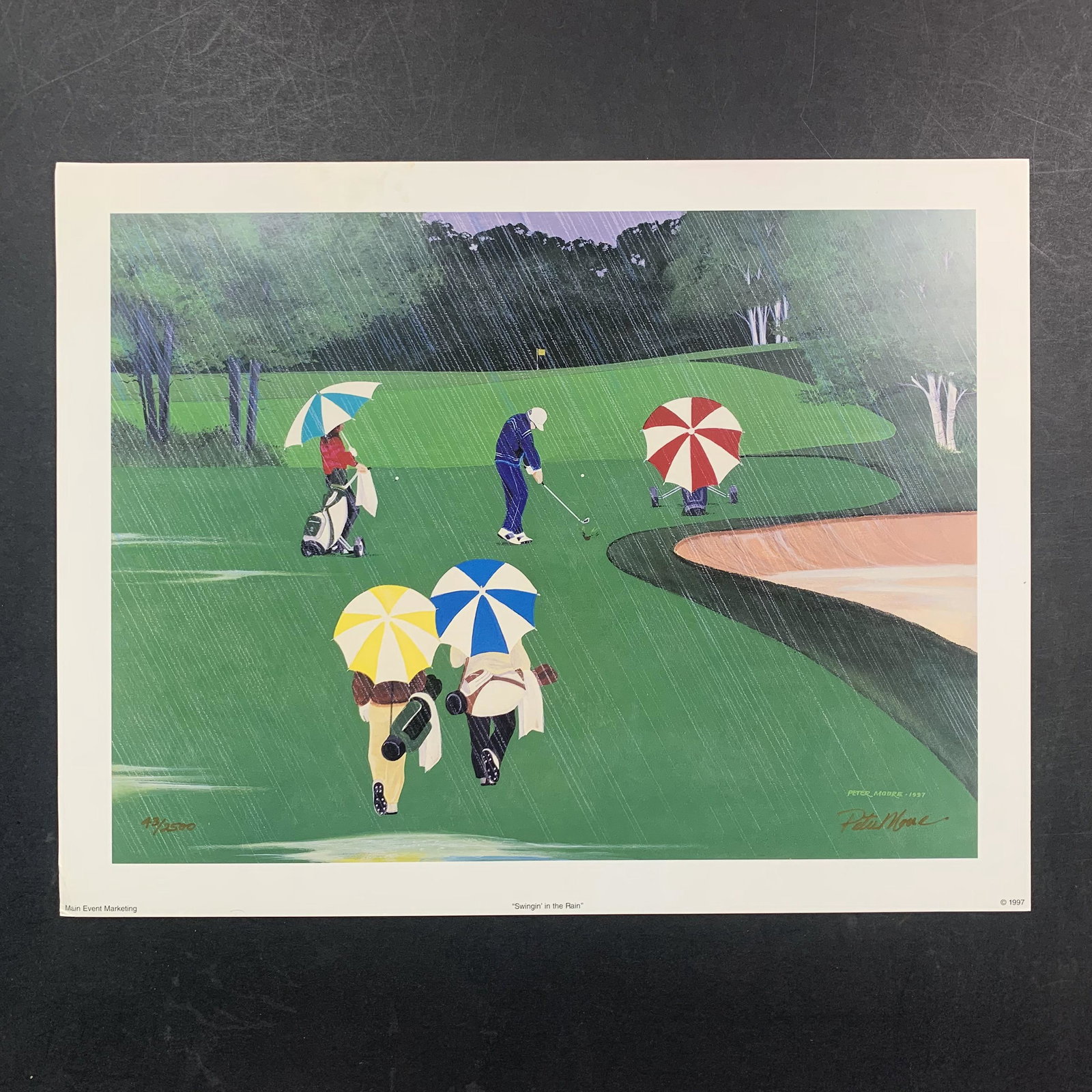 Peter Moore's "Swingin' in the Rain" Limited Edition Print: Peter Moore's "Swingin' in the Rain" Limited Edition Print. A man hits a golf ball towards the hole during a rainstorm while others look on. Signed on the bottom right and numbered 43/2500 on the bott