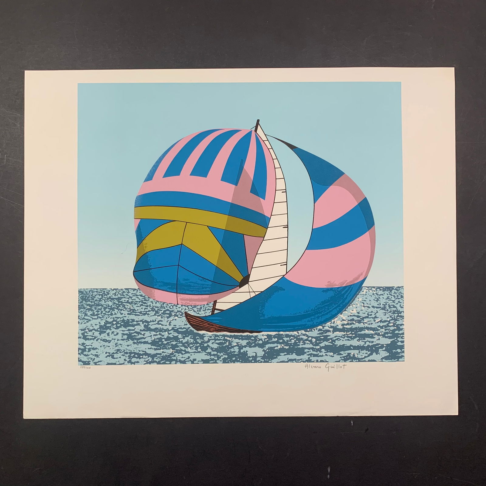 Alvaro Guillot's "Love Boat" Limited Edition Print: Alvaro Guillot's "Love Boat" limited edition print, signed lower right and numbered 189/300 lower left. This piece is of a small boat with blue and pink sails. This piece is in excellent condition. Im