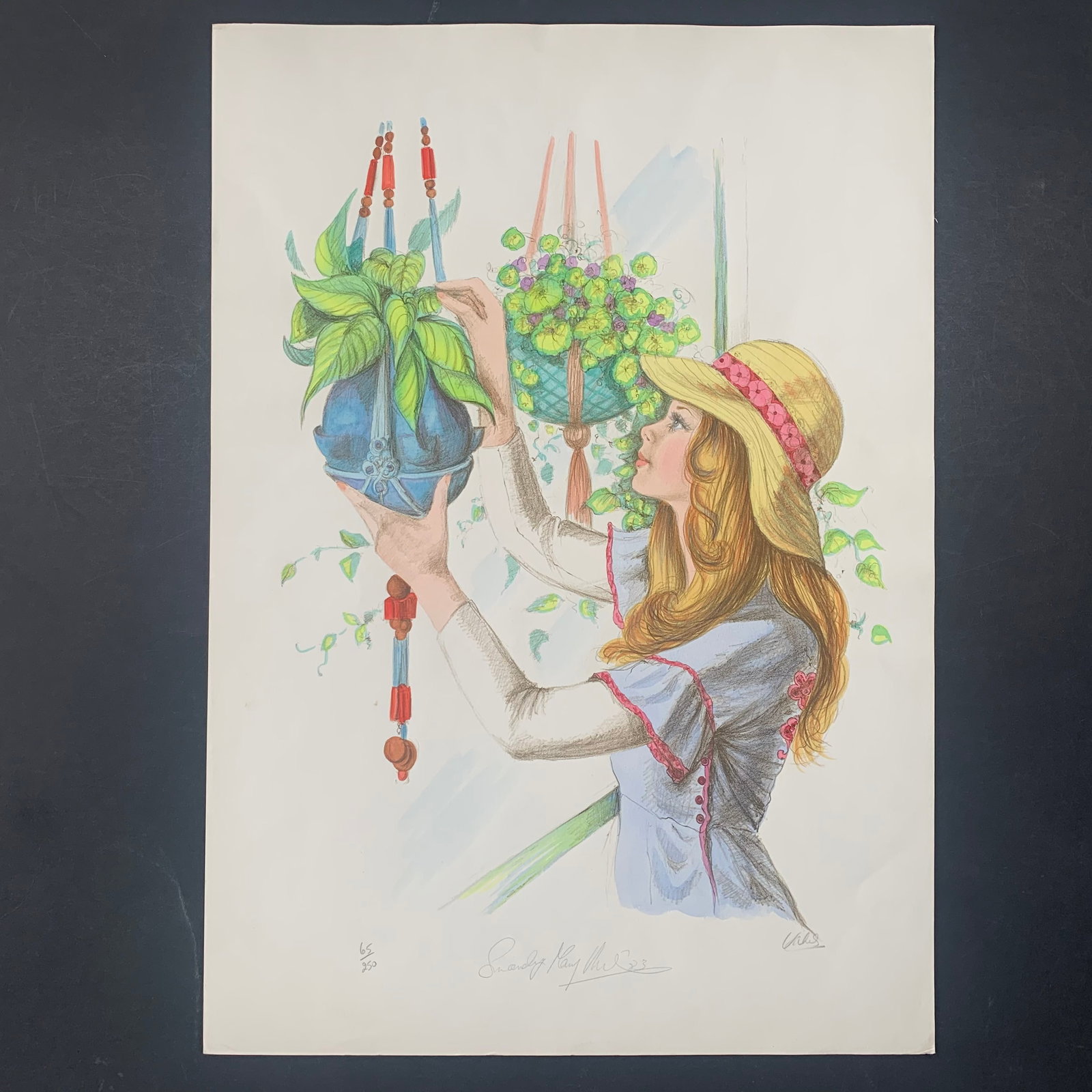 Mary Vickers' "Jeanna" Limited Edition Print: Mary Vickers' "Jeanna" limited edition print, signed lower right and numbered 65/250 lower left. This piece is of a younger woman wearing a hat, tending to a plant in a hanging planter. This piece is 