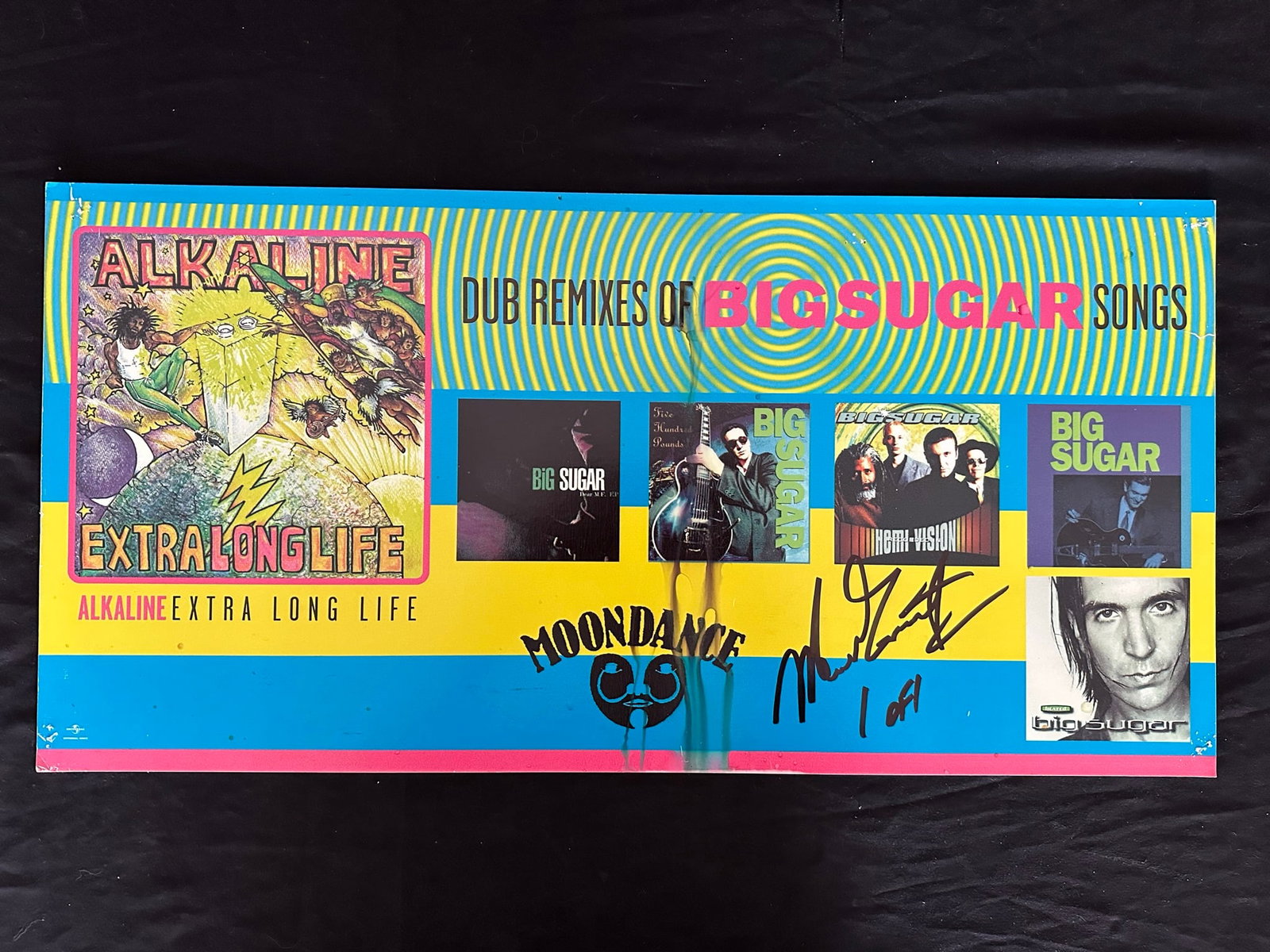 Alkaline "Extra Long Life" Dub Remixes of Big Sugar Publicity Poster: Alkaline "Extra Long Life" Dub Remixes of Big Sugar out of print Moondance cardboard publicity poster, signed 1 of 1. This piece shows pinholes in the corners, and some moisture damage in the middle.