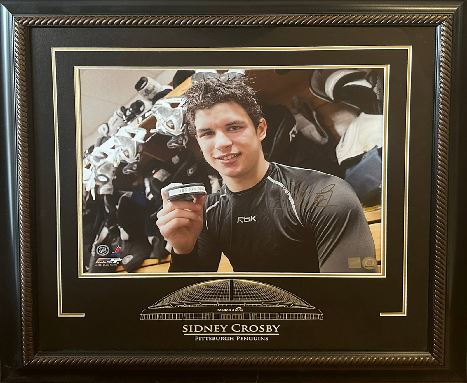 Framed Sidney Crosby Autographed 16x20 Photo - 1st NHL Goal Puck - COA by Frameworth: Up for auction is an exceptional piece of NHL memorabilia: an officially licensed 16" x 20" framed color photograph of Pittsburgh Penguins superstar Sidney Crosby, personally autographed and authentic