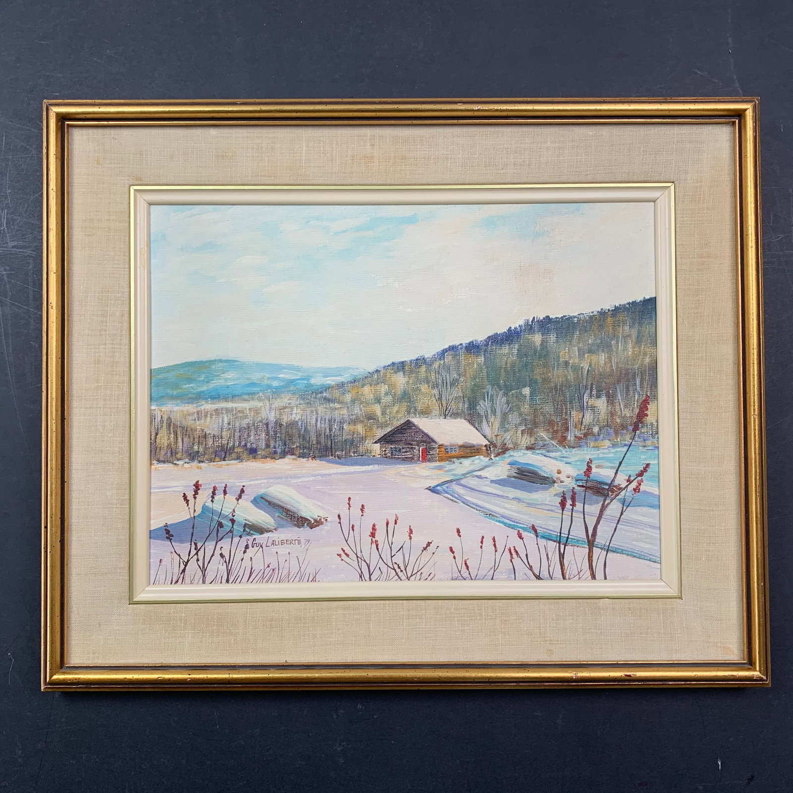 Guy Laliberte Original: Guy Laliberte's "Le Shack", circa 1979, original acrylic on canvas board painting, signed and dated lower left. This piece is of a scene of a cabin in the winter, with a large mountainous forest in th
