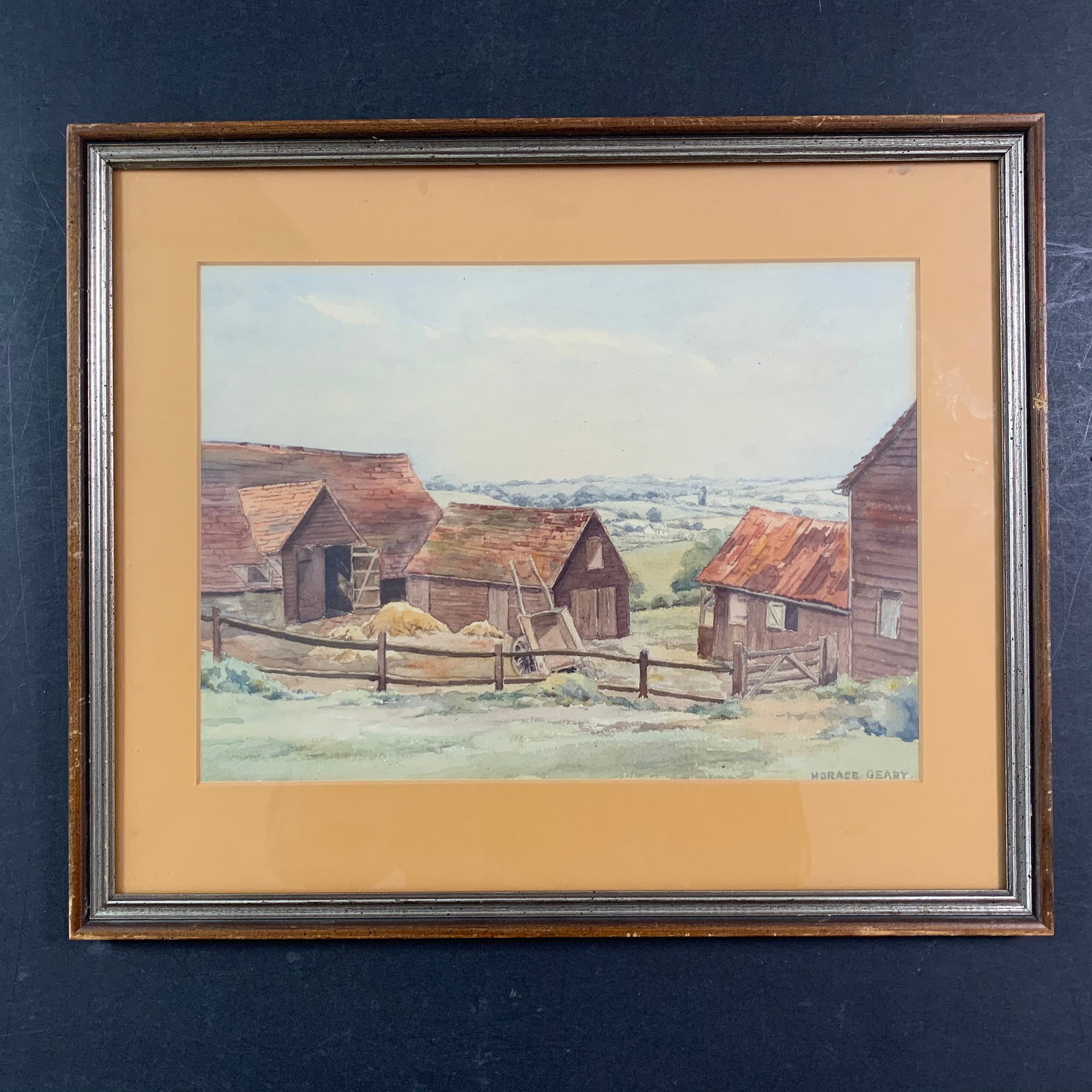 Horace Geary Original: A Horace Geary original watercolour on paper painting, signed signed lower right. This piece is a scene of a couple small barns atop a hill, overlooking a large green landscape. This piece is in excel