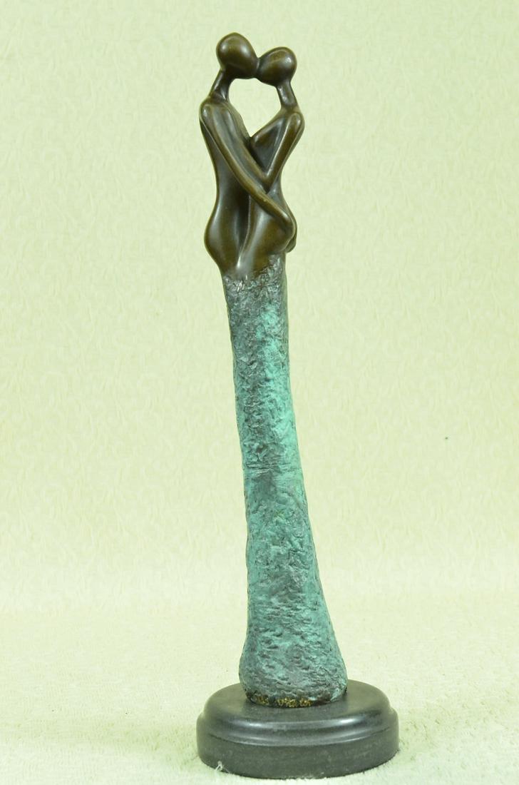 Abstract First Kiss Bronze Statue on Marble Base: The suggestive male and female figures, in an act of true affection, make a connection. With interlocked arms and lips, they initiate the integration of two souls becoming one. The green patina coated
