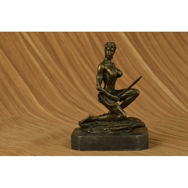 Amazon Woman With Sword Bronze Statue: A sexy and tough Amazon warrior sits proudly holding her sword. Her other arm is tense, highlighting her sculpted arms. Her large breasts are dressed in a studded bikini. She is a fighter in the wild.