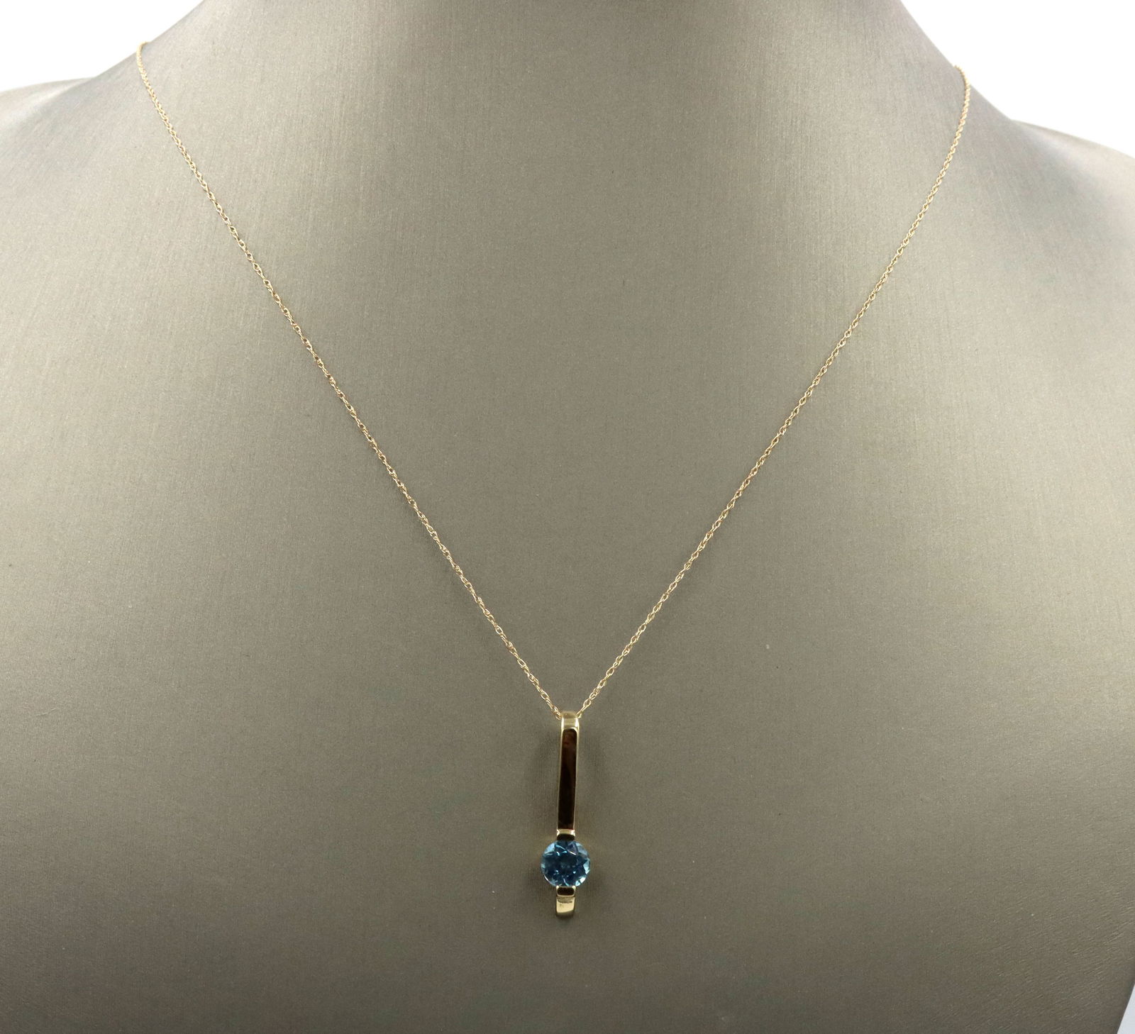14kt Yellow gold blue topaz bar pendant on chain: 14kt Yellow gold blue topaz bar pendant on 18-inch chain necklace with spring ring clasp. The total weight of the necklace is 1.80 grams.