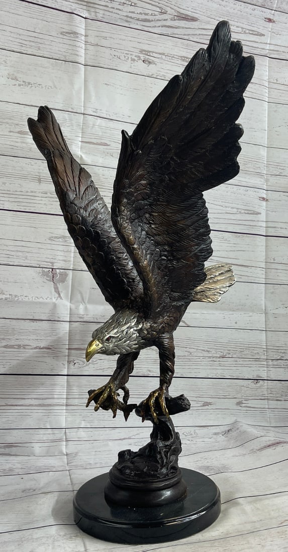 Eagle Catch Fish Bronze Sculpture: A fascinating and eye-catching sculpture. A large eagle spreads it is wings and prepares for flight. His large wings arch high above him. His talons prepare to release the wood it clutches. His intens