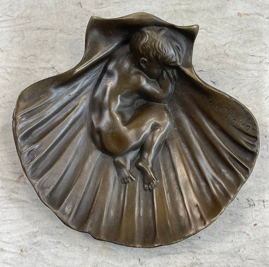 Boy Ashtray Bronze Sculpture: This delicate piece features a naked little boy asleep in a scallop shell. He is curled up in a ball, sleeping so peacefully that it appears that his body is almost fused with the structure of the she